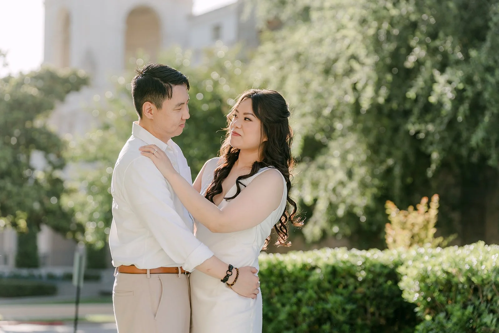 Emily rests her head on James's shoulder beside the garden hedges at Pasadena City Hall.