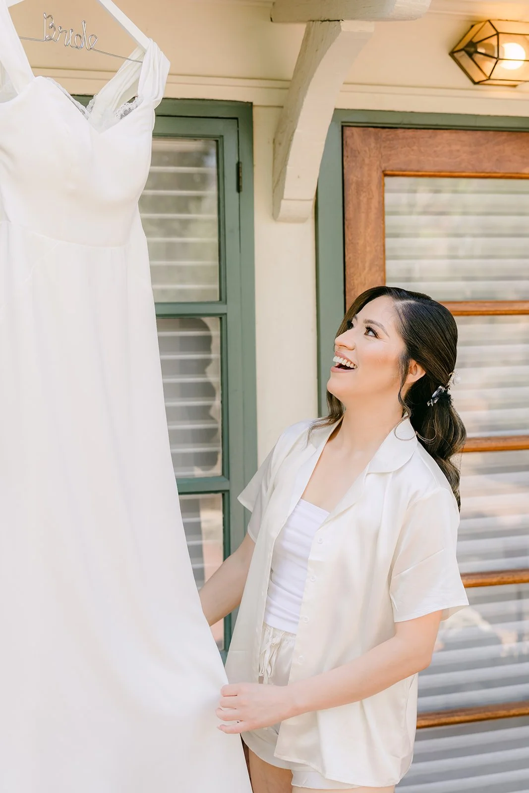 Mariana smiling up at her gown hanging outside the Padua Hills bridal suite