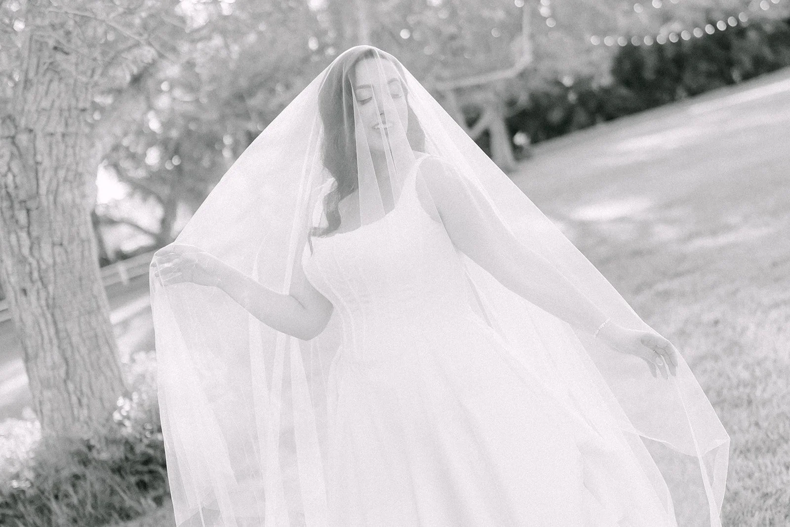 Black and white portrait of the bride lifting her cathedral veil
