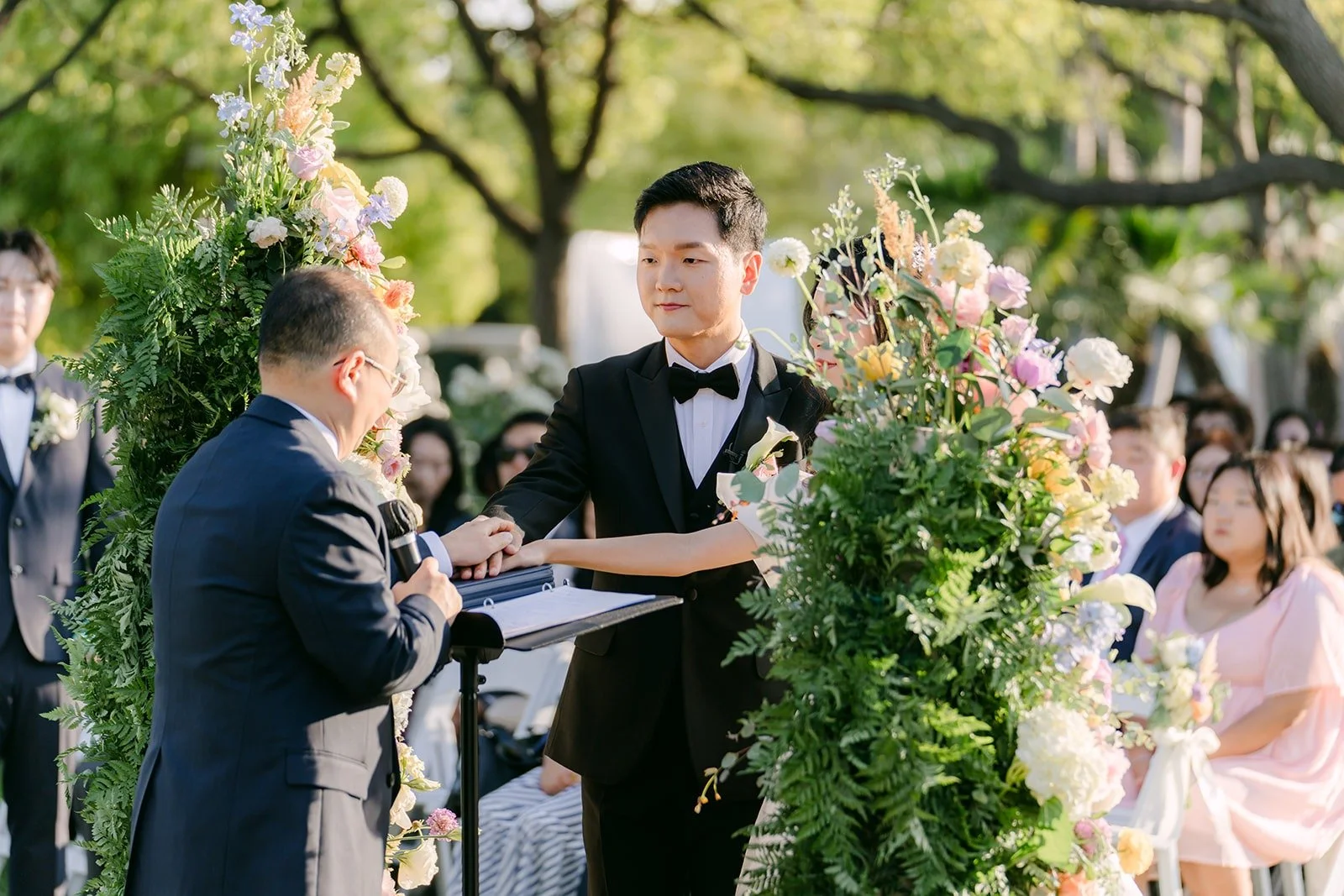 Jeannie and Eunsang at the front of the ceremony framed by greenery