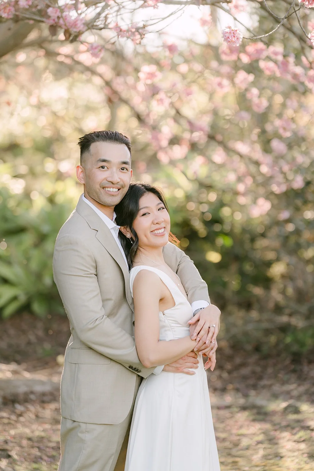 Kim leaning into Vincent's chest under the blossoming branches.