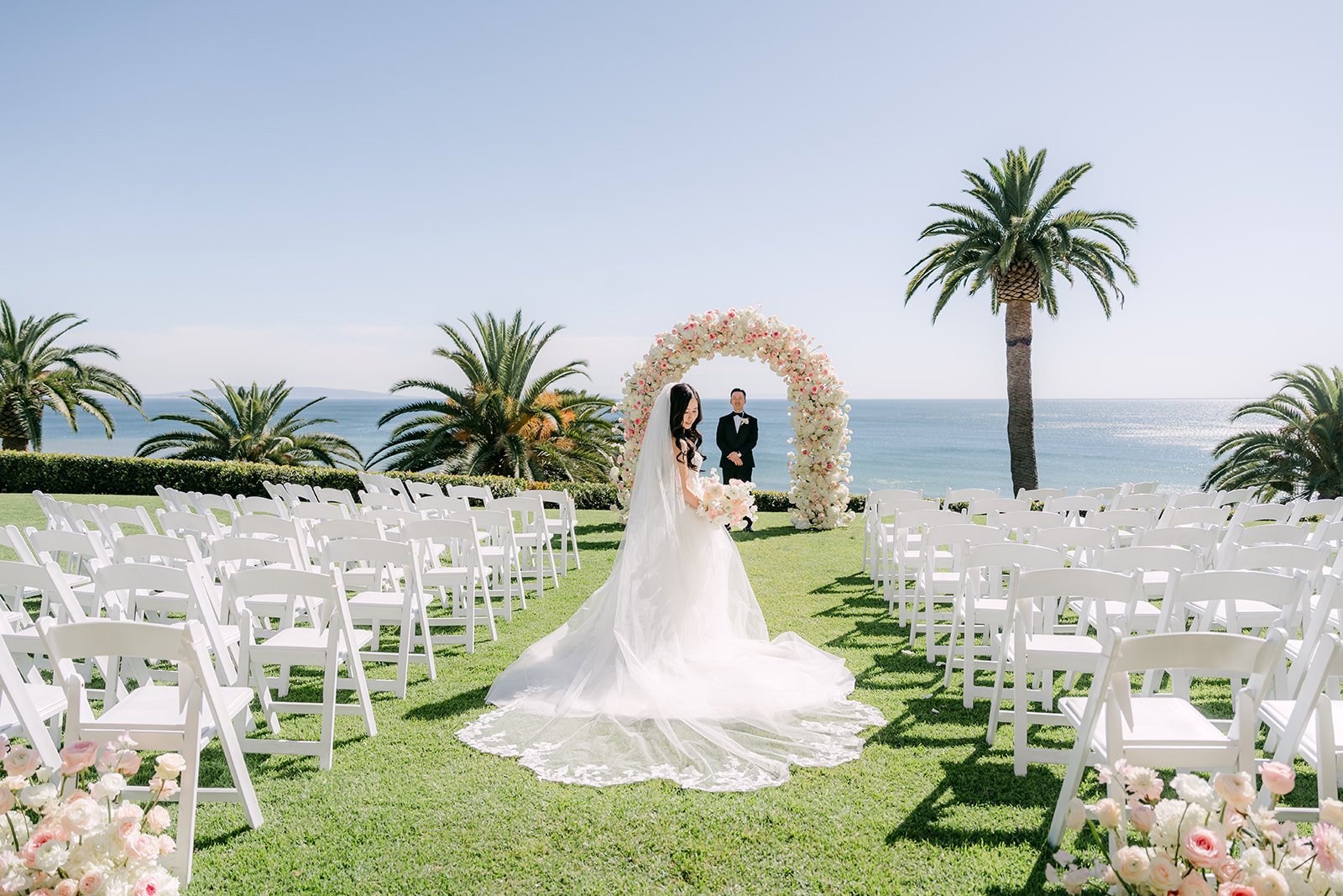 Couple at the ceremony arch with the ocean behind them