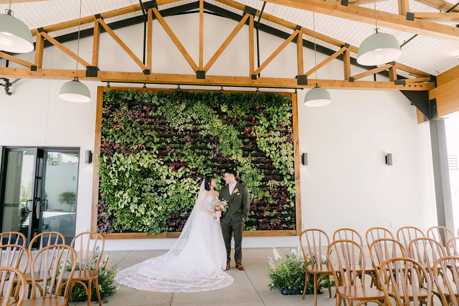 Wide view of the couple at the living wall under the Pavilion trusses