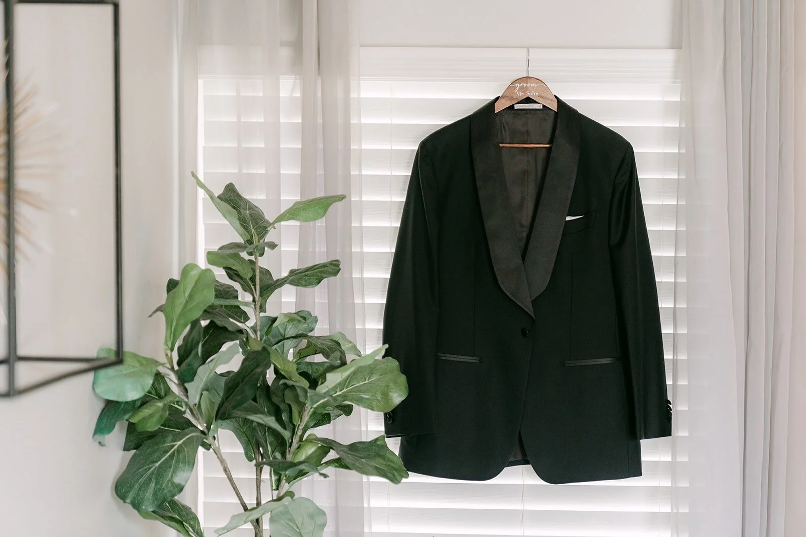 William's black tuxedo jacket hanging by the window