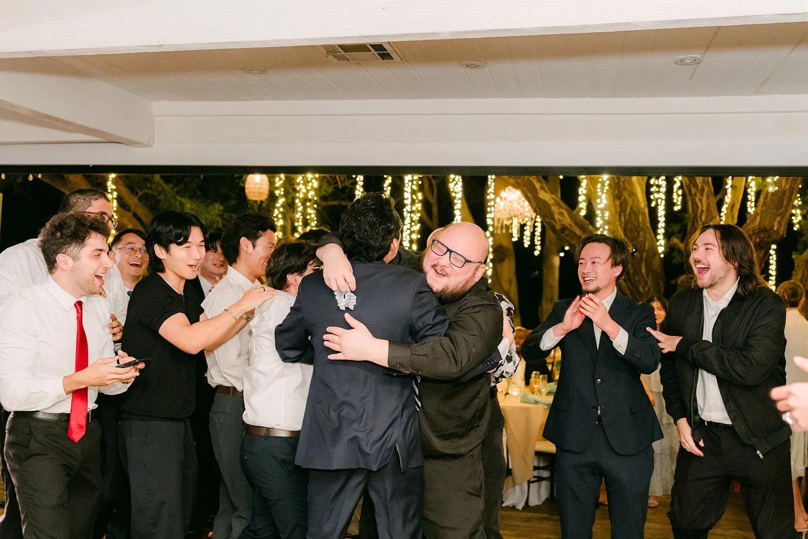 Groomsmen hugging and cheering after the garter toss