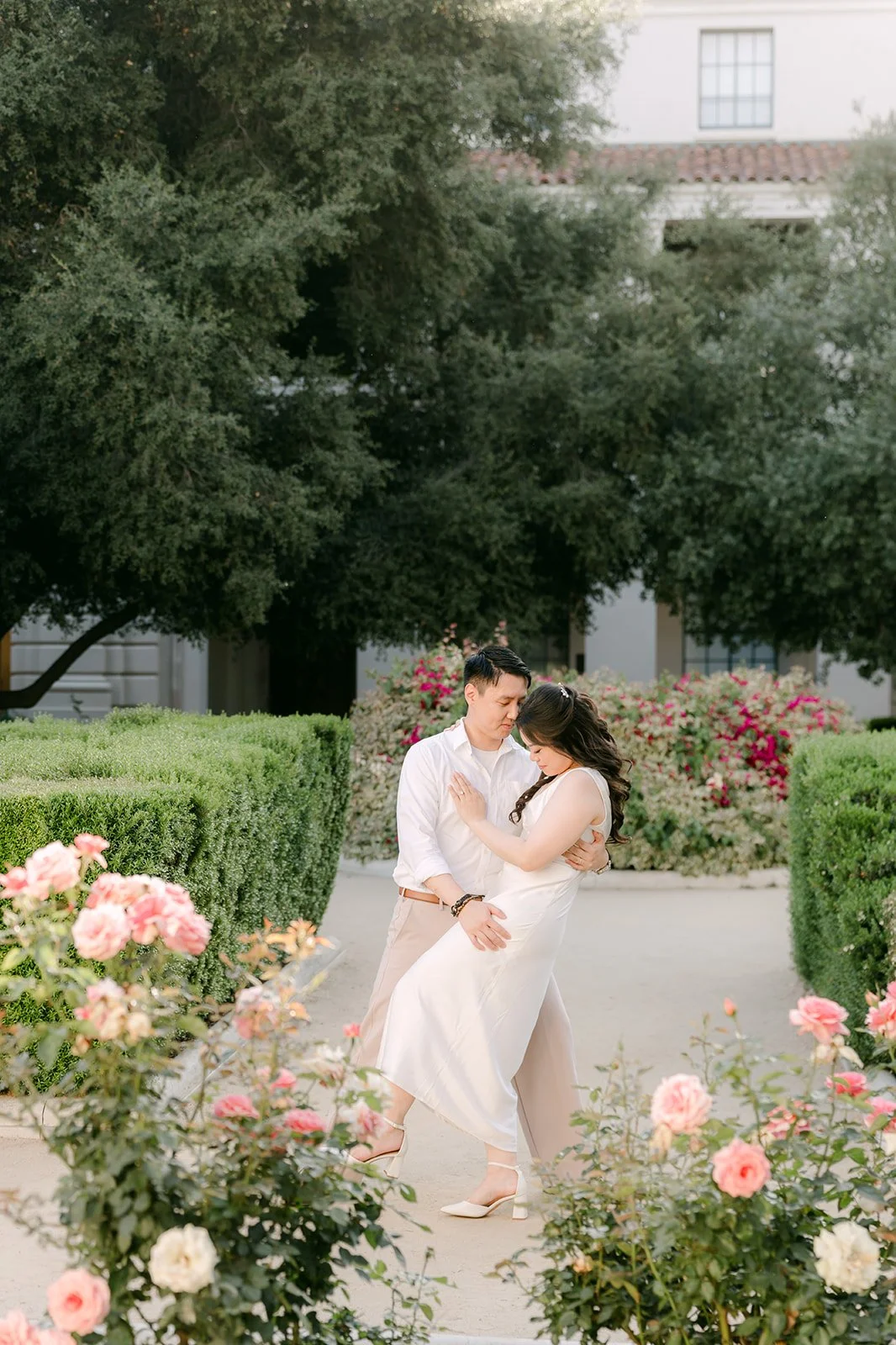 Emily and James share a laugh among pink roses in the courtyard garden at Pasadena City Hall.