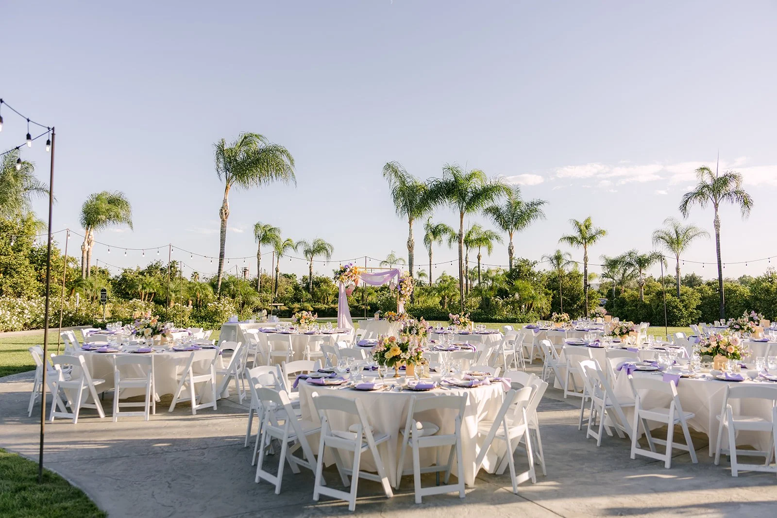 Reception tables on the patio at The Grove of Redlands with palms behind them.