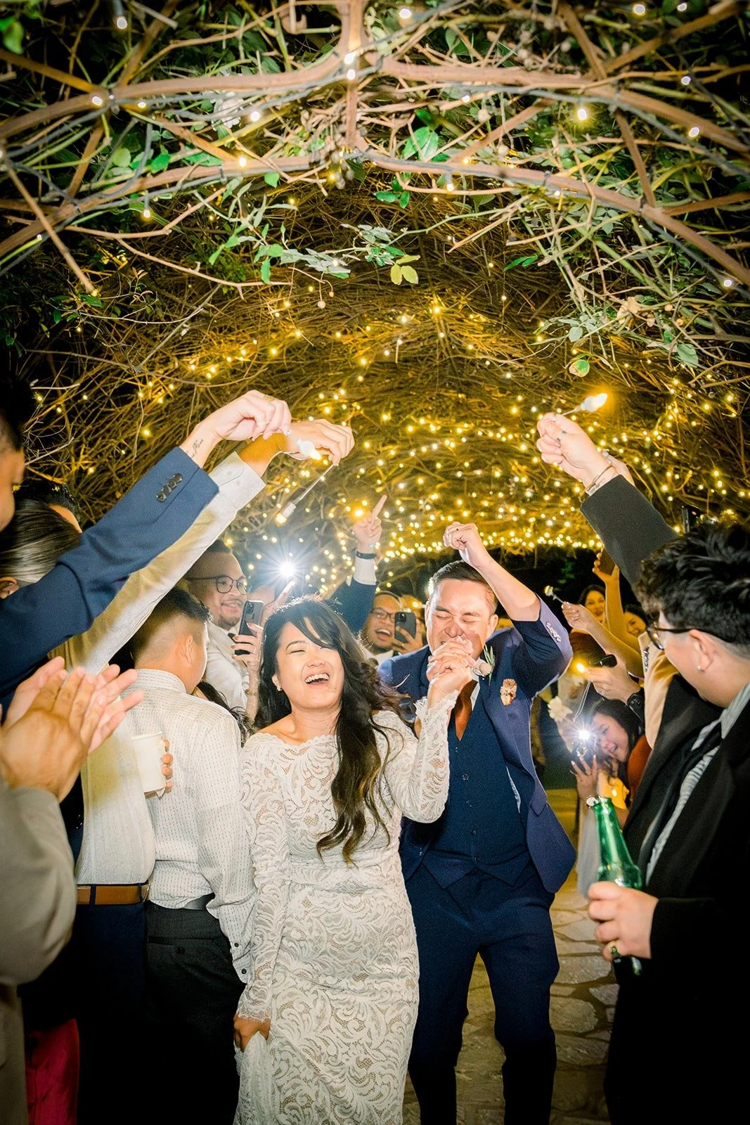 Hannah and Vincent walking through the lit tunnel as guests cheer