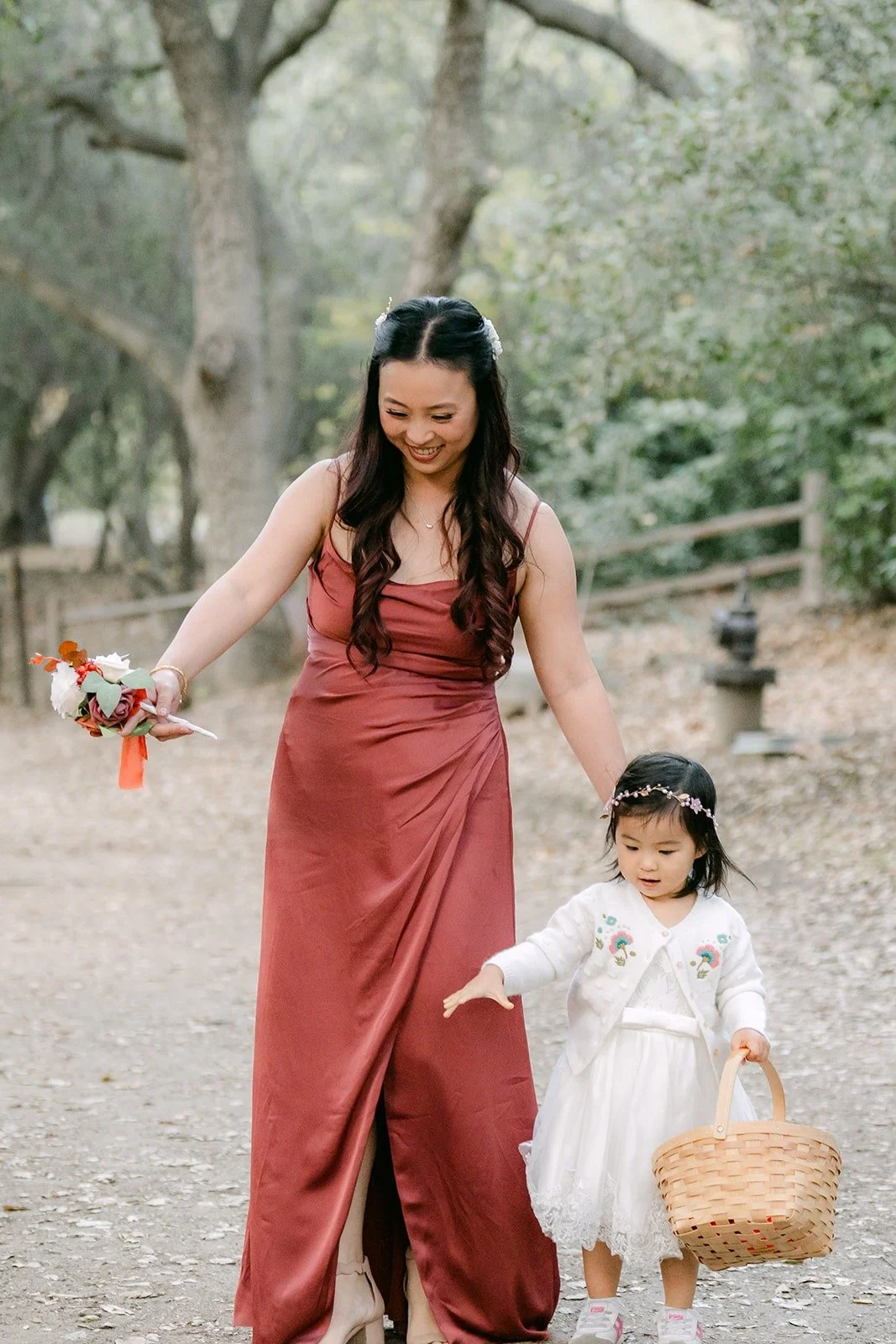 A bridesmaid in a rose gown walks the flower girl down the aisle