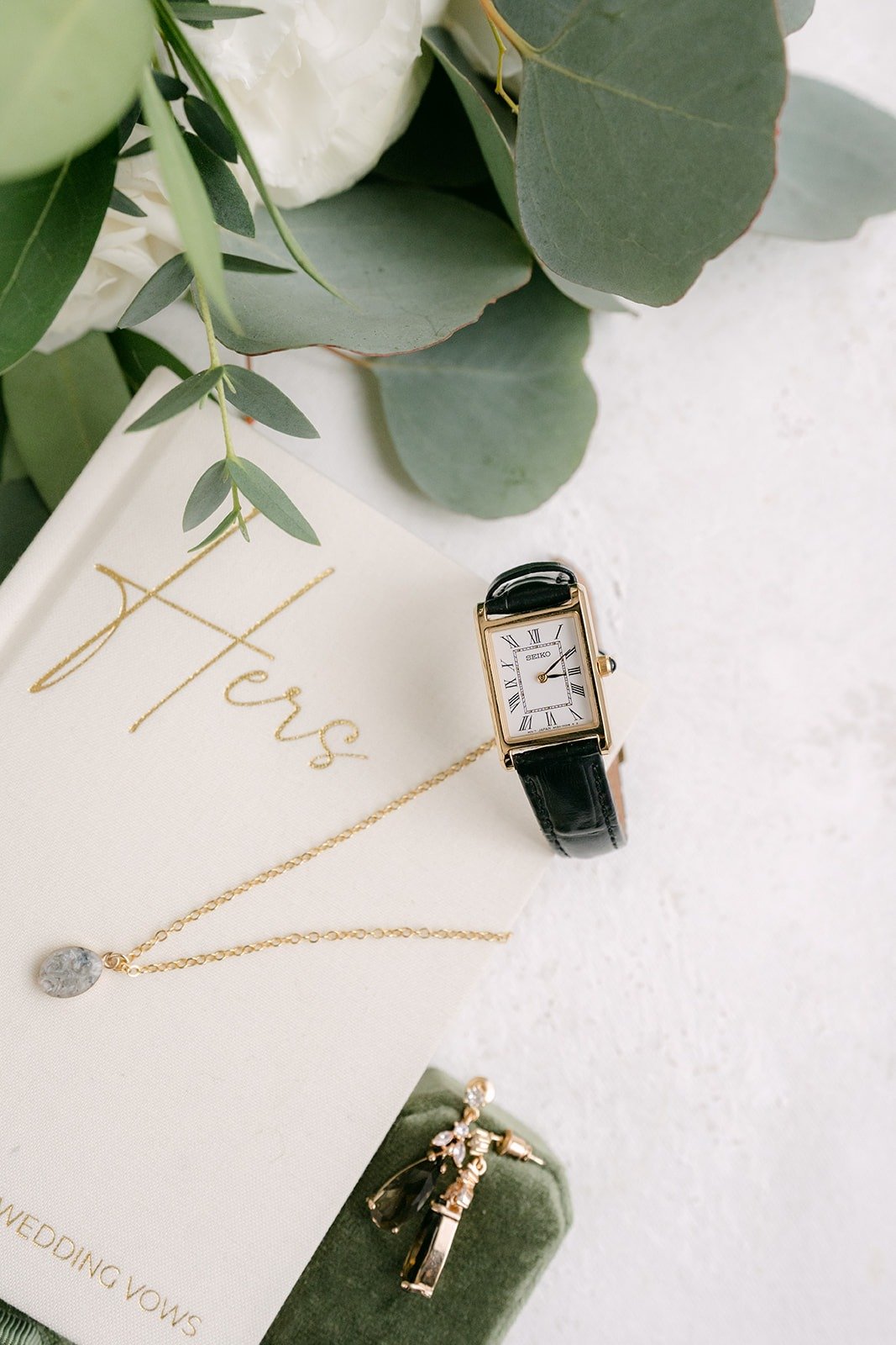 Vivian's Hers vow book with a gold watch and earrings