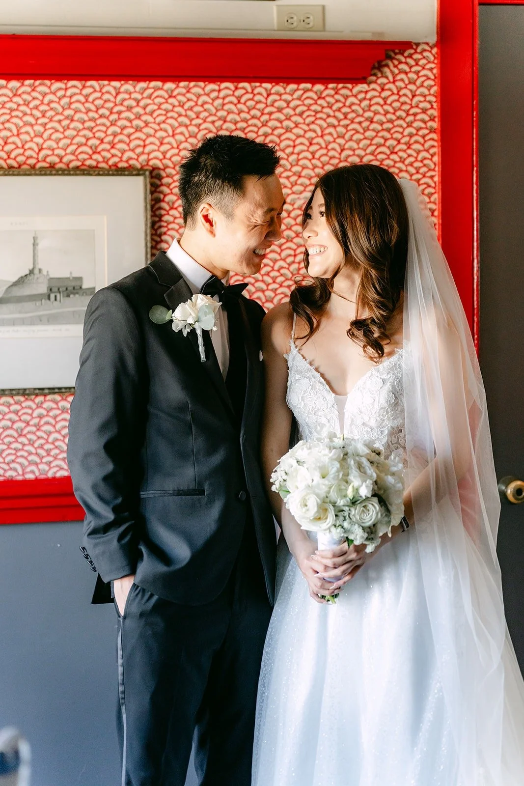 Valerie and Jason close together against the red patterned wall