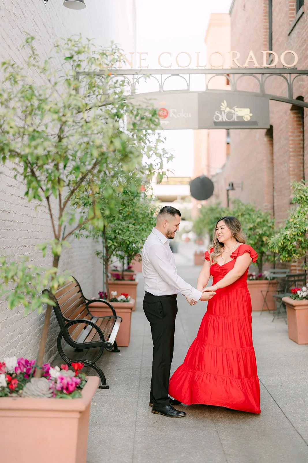 Linh and Ankush share a moment beside a bench and flower planters in an Old Town paseo.