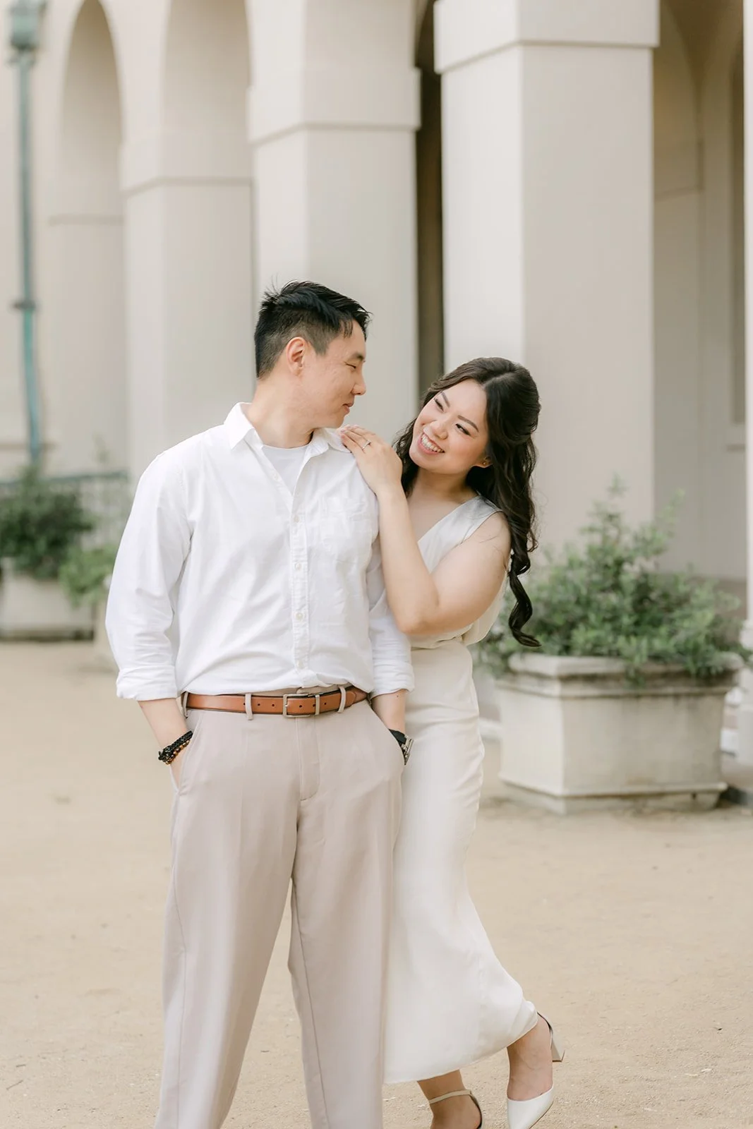 Emily and James stand close beneath the arches at the edge of the courtyard.