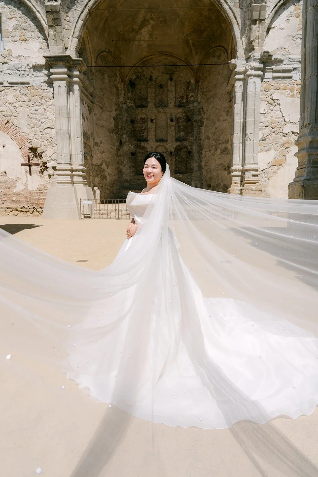 Chorok's long veil trailing across the ground in front of the stone ruins at the Mission