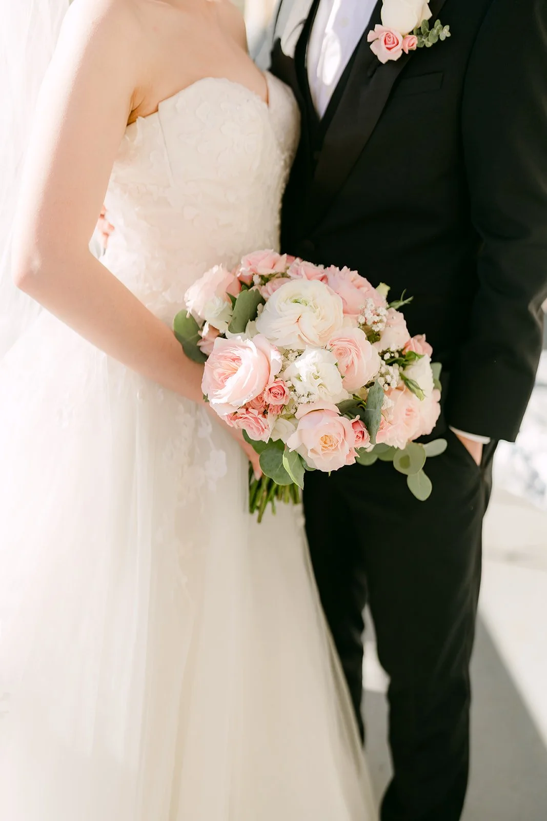 Bride's blush rose bouquet against the groom's black tuxedo