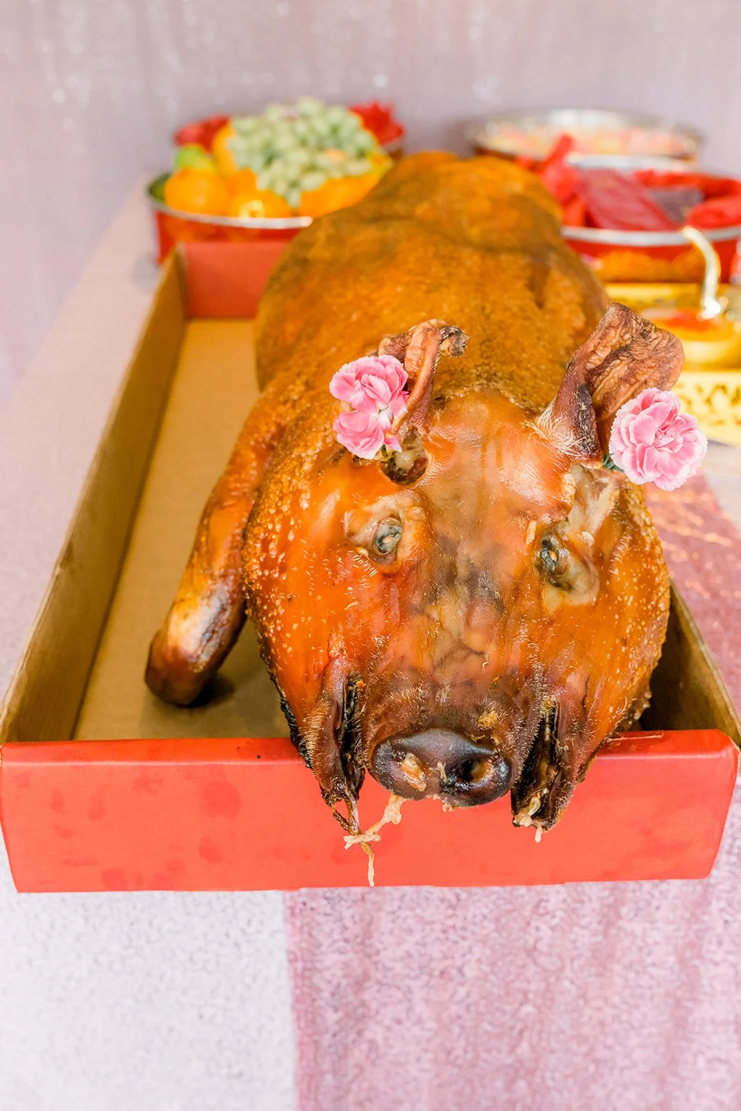 A roast pig decorated with flowers presented as a wedding gift.