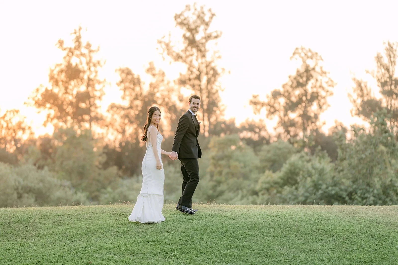 Stephanie and Kevin walking across the Sterling Hills lawn at sunset