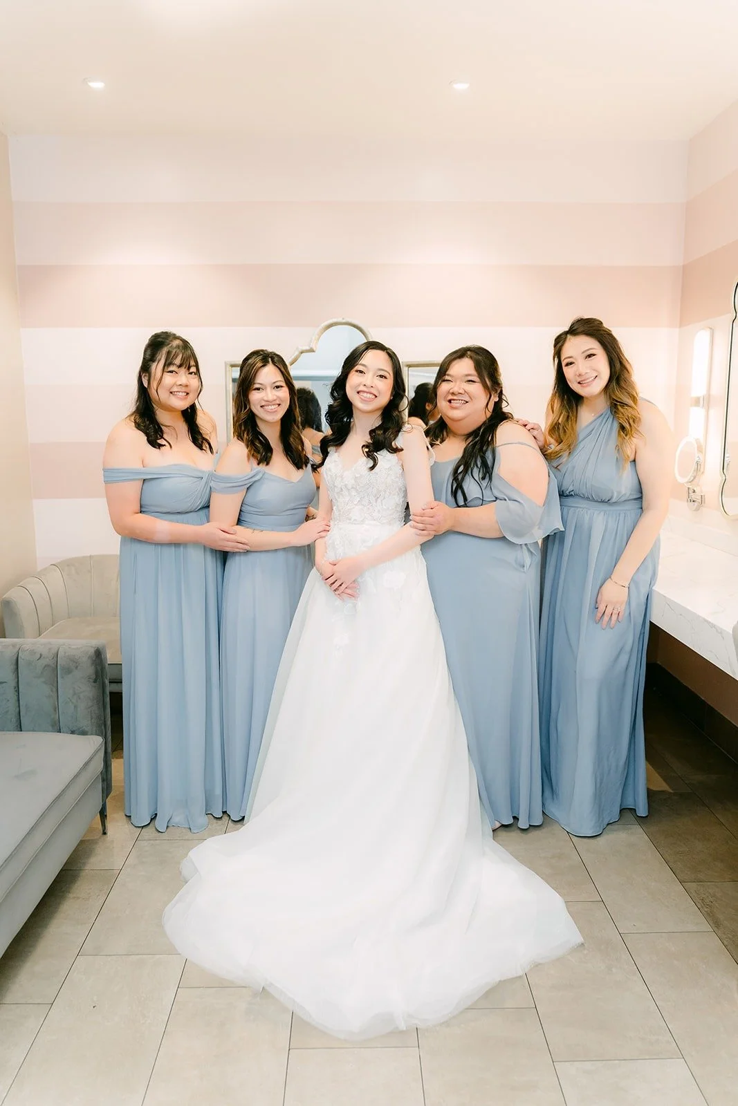 Natalie in her gown with her bridesmaids in dusty blue dresses in the bridal suite at Rio Hondo, photographed by One and Only Production