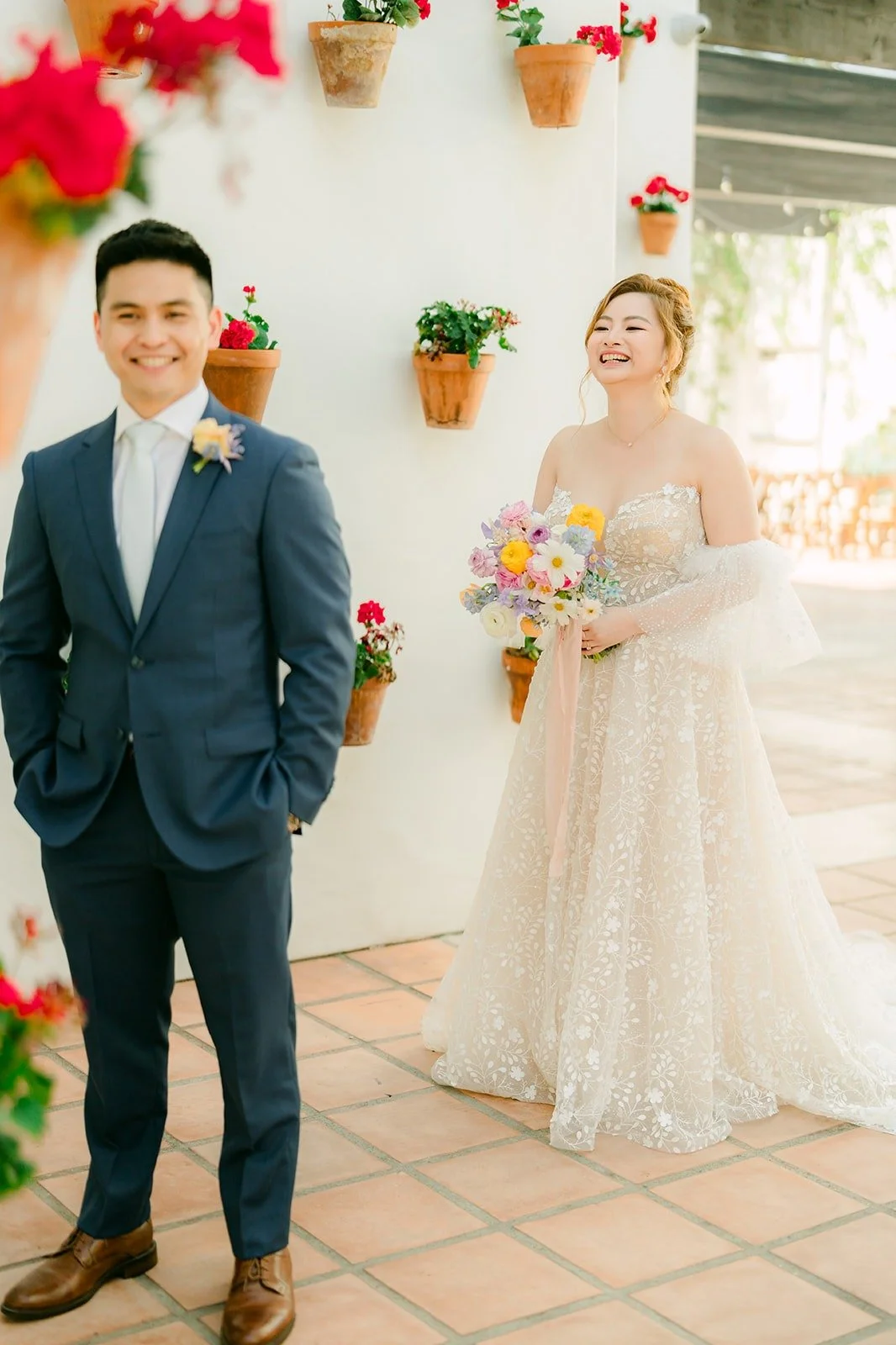 Joanna walking up behind Jerrick with her pastel bouquet