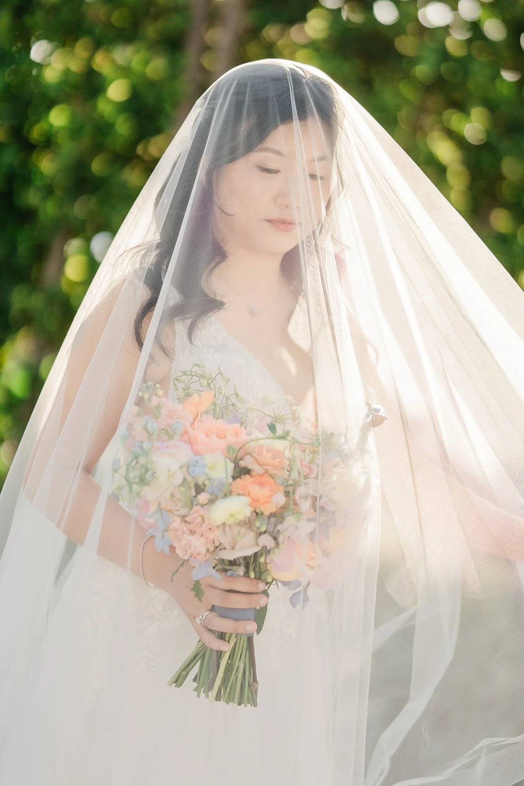 Constance under her veil holding her pastel bouquet