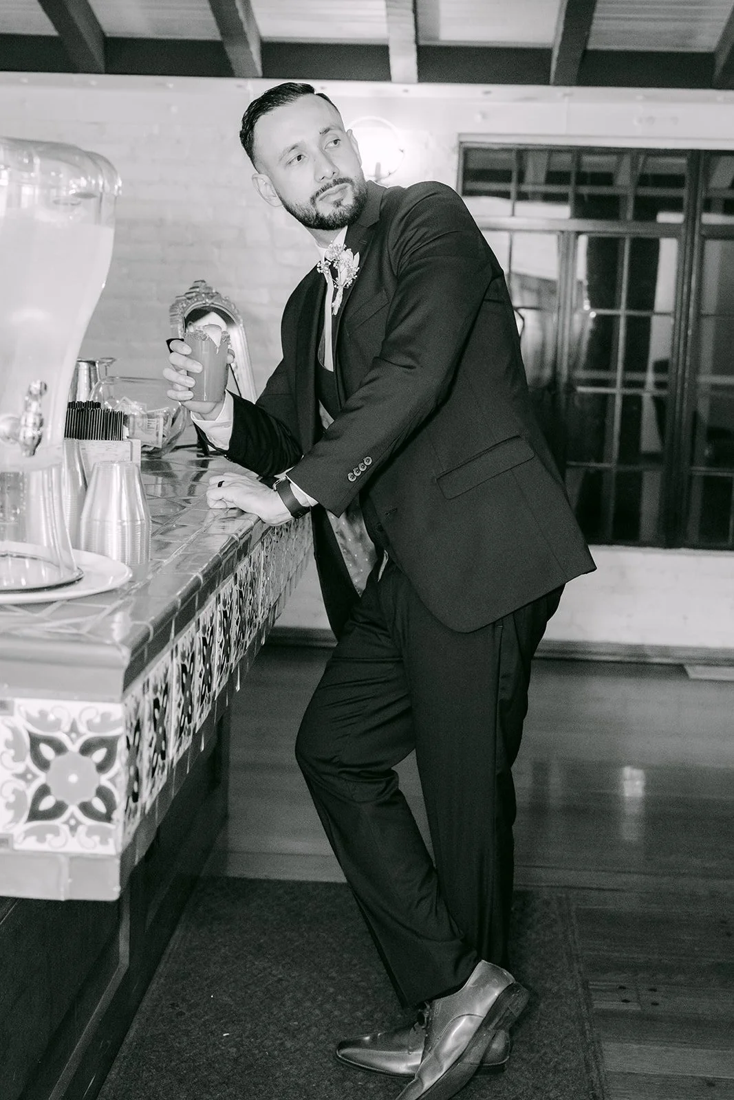Black and white portrait of Danny leaning on the tiled counter, photographed by One and Only Production