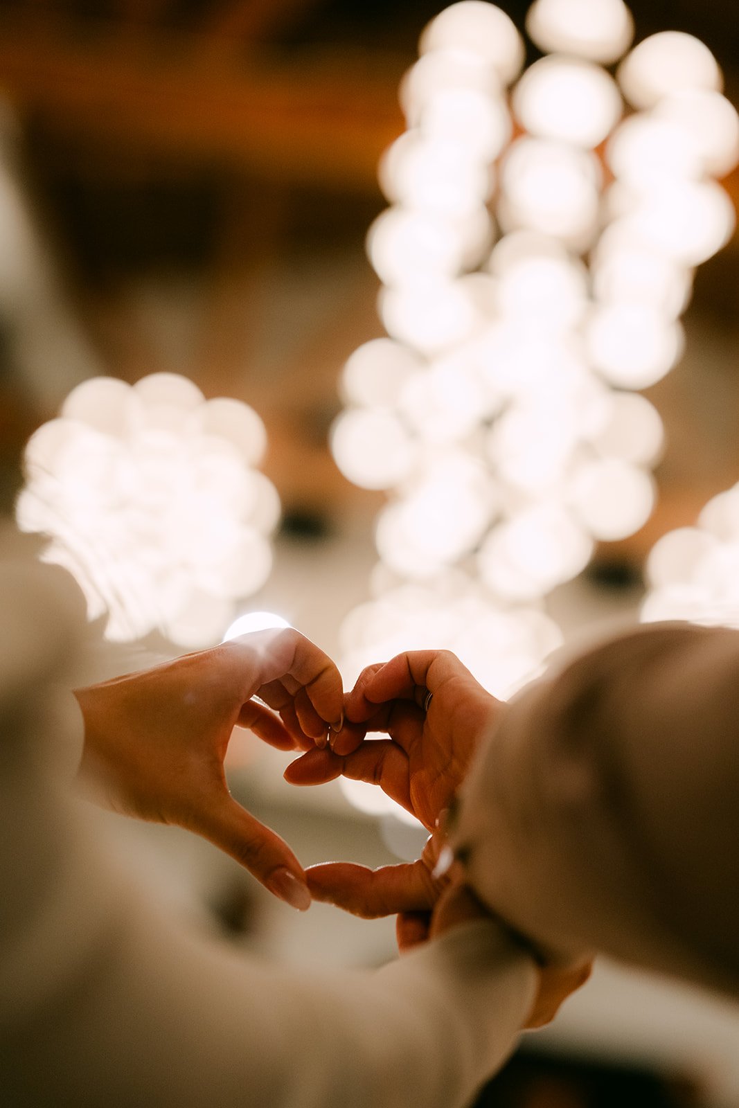 Denise and Michael making a heart with their hands in front of glowing lights.