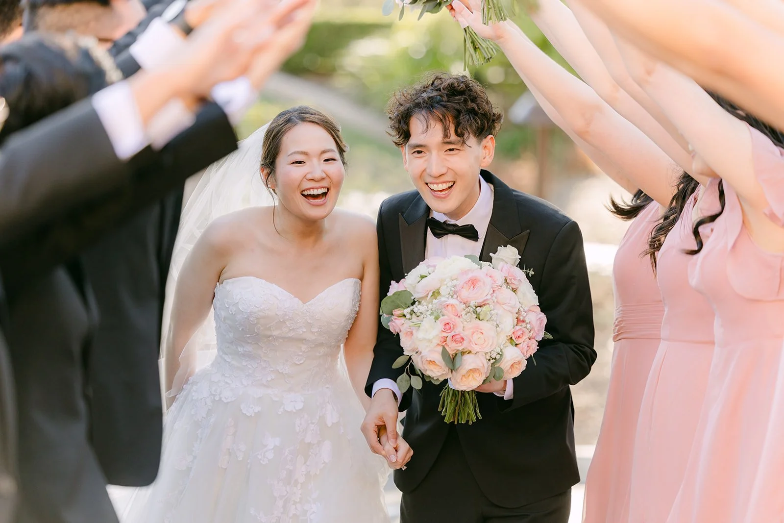Bride and groom laughing as the wedding party cheers around them