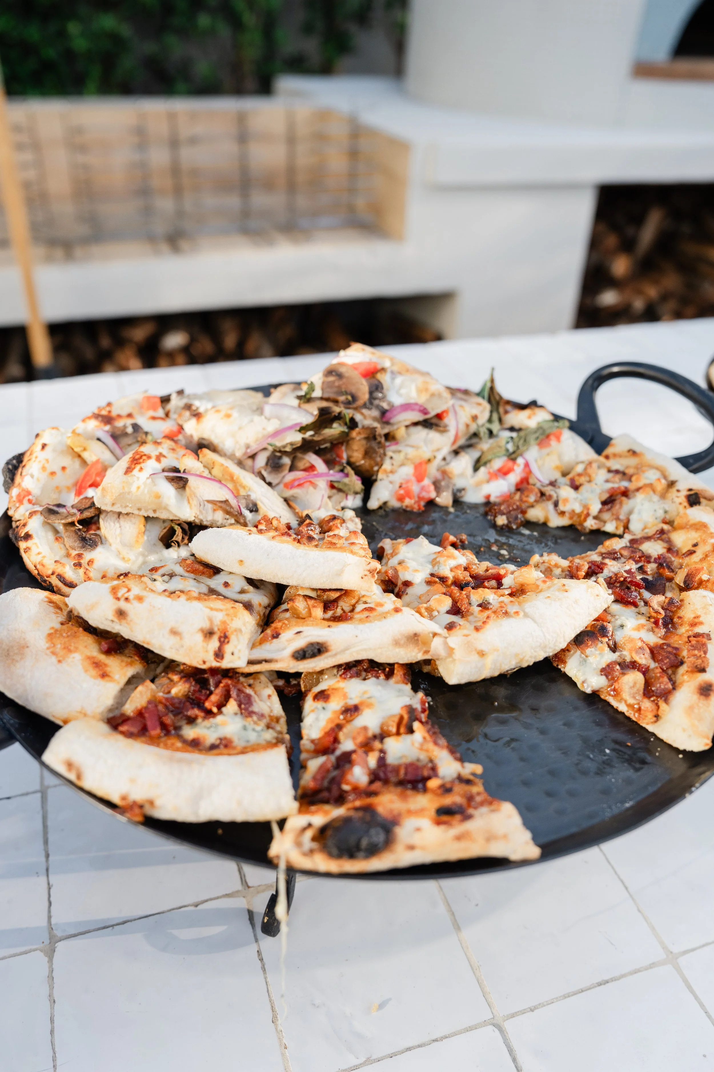 Pizza slices on a black grill tray with a white tiled floor beneath.