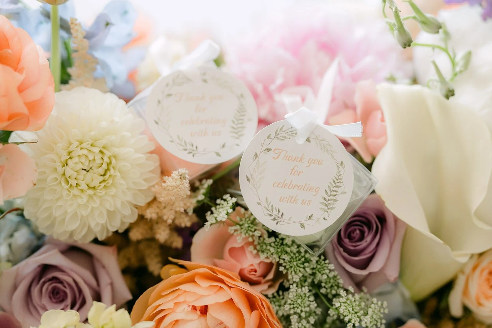 Wedding favors tucked among pastel roses, photographed by One and Only Production
