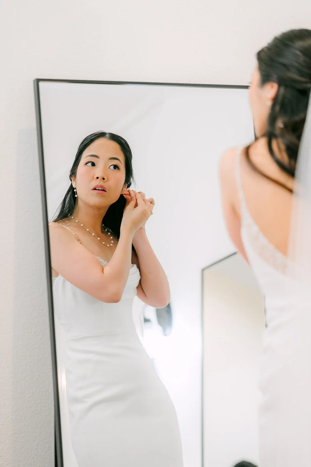 Stephanie putting on an earring in front of a tall mirror at Sterling Hills