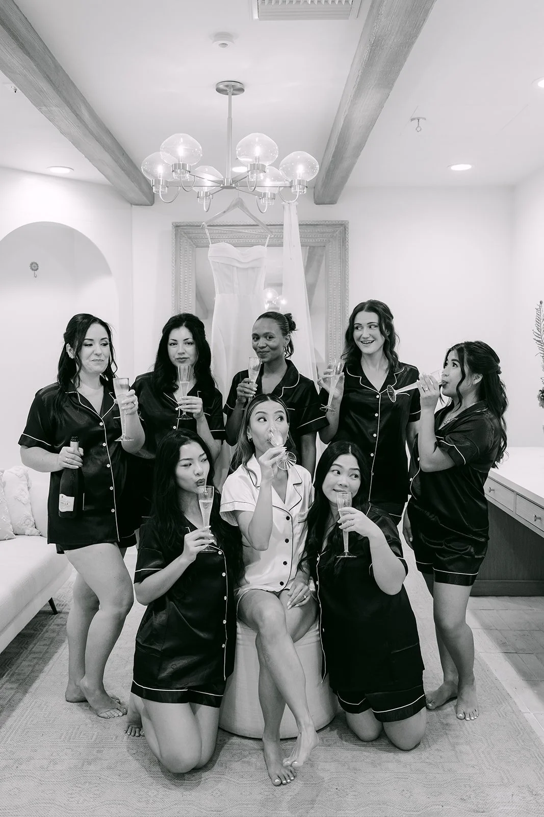 Black and white photo of the bridal party in matching robes laughing in the suite