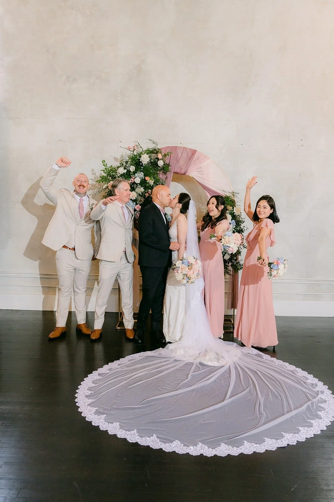 Elisa and Brandon with their full wedding party, her train spread in front of them