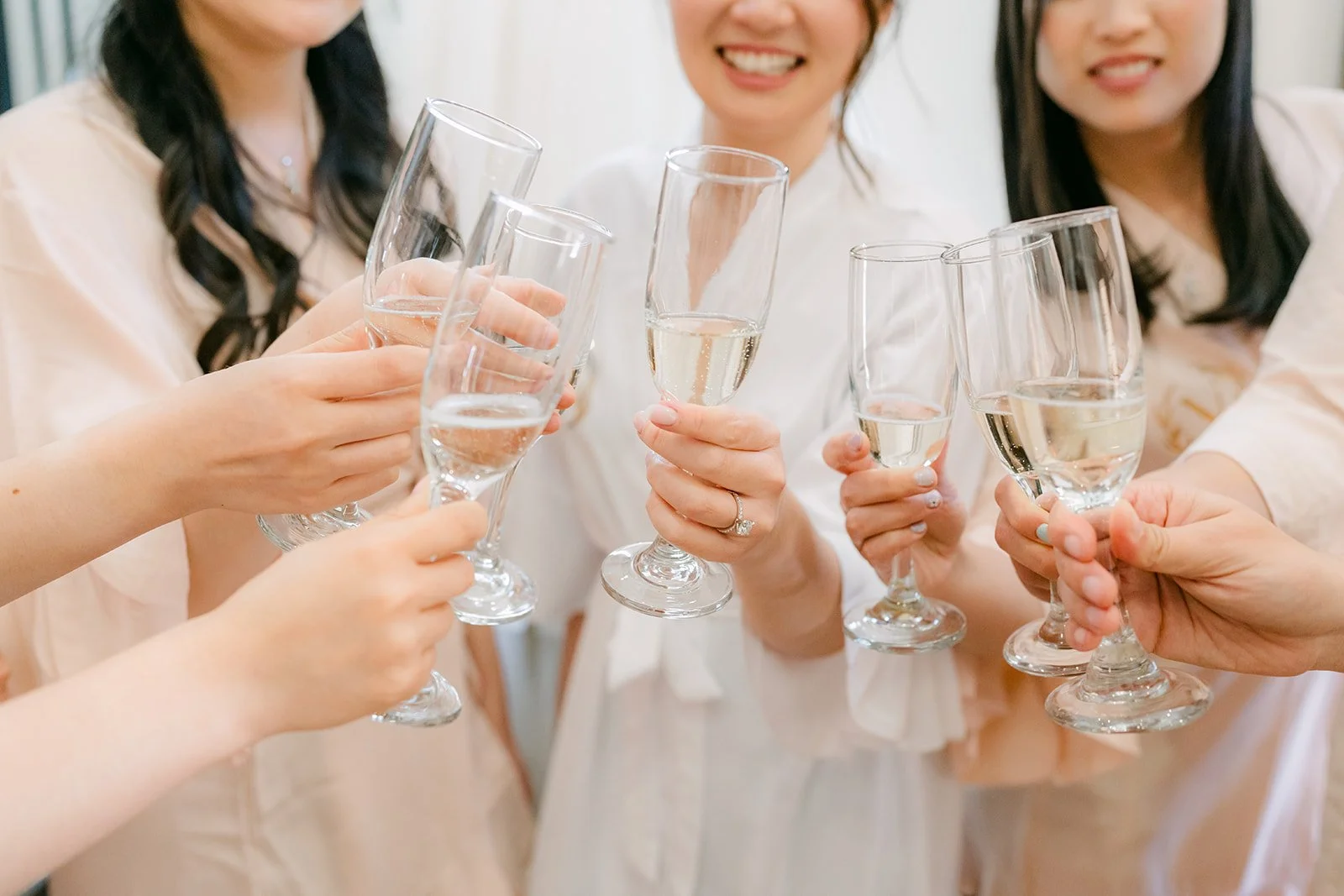 Bride and bridesmaids clinking champagne glasses