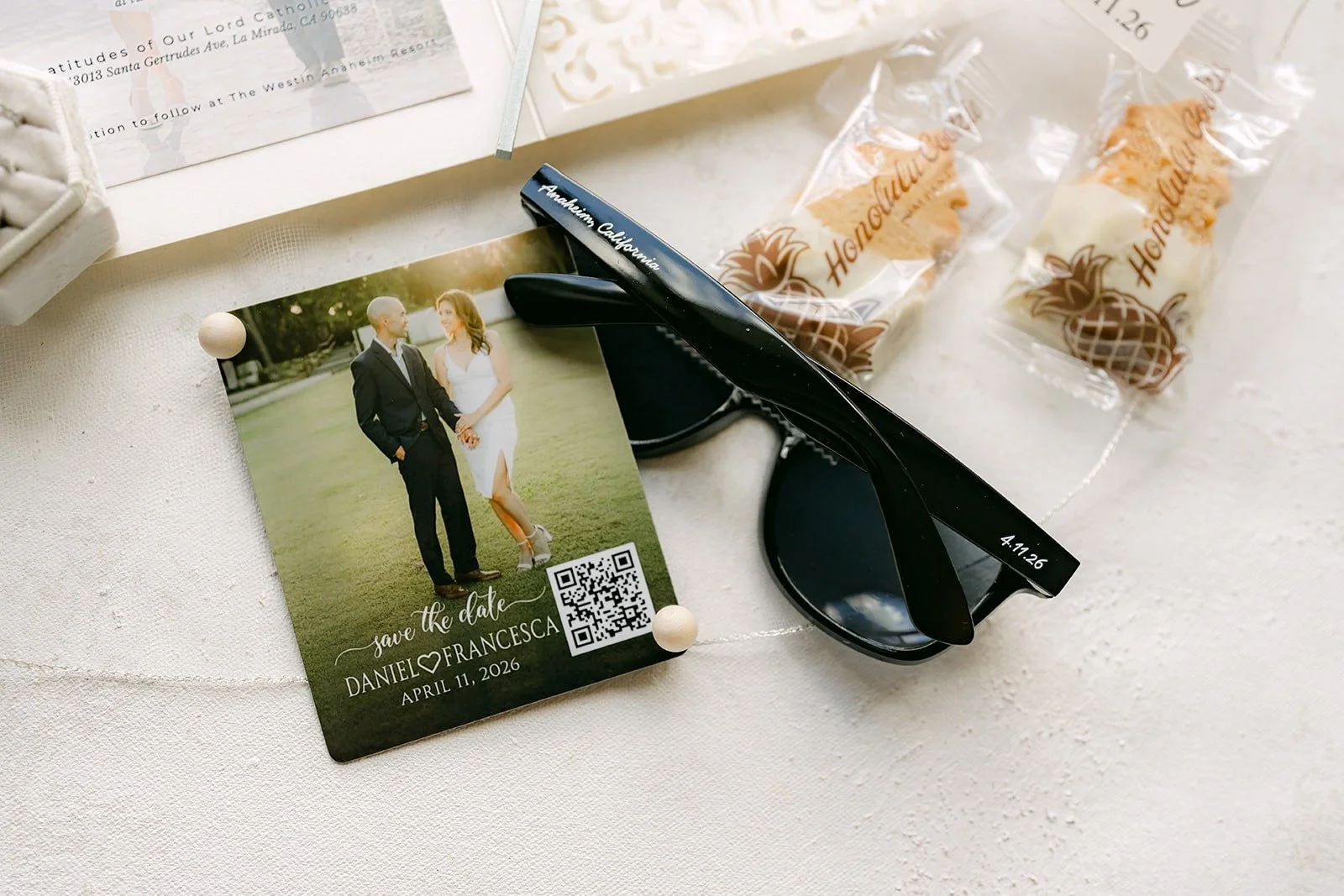 Engagement photo card styled with black sunglasses and wrapped favors