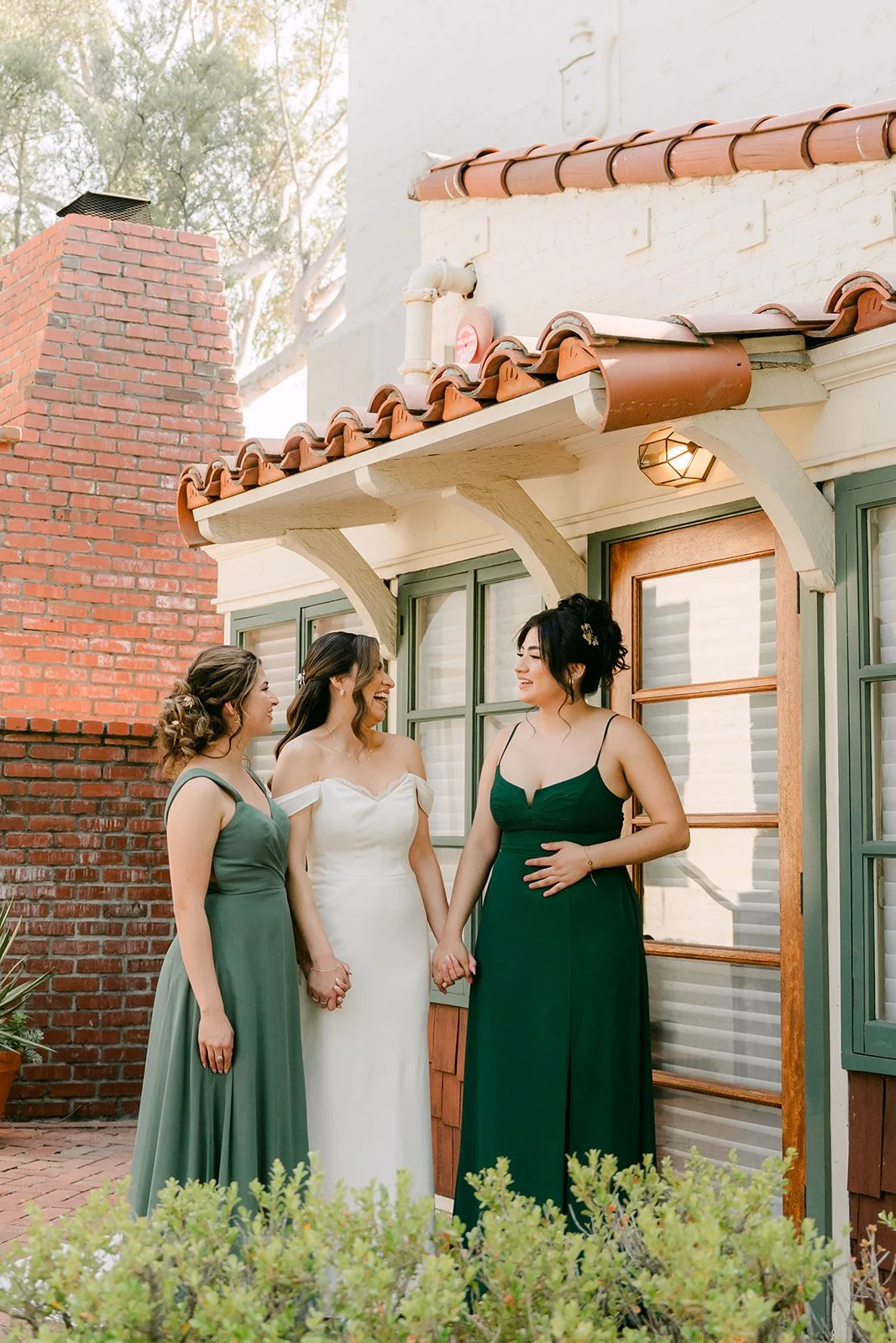 Mariana with two bridesmaids in green under the clay tile roof of the bridal suite