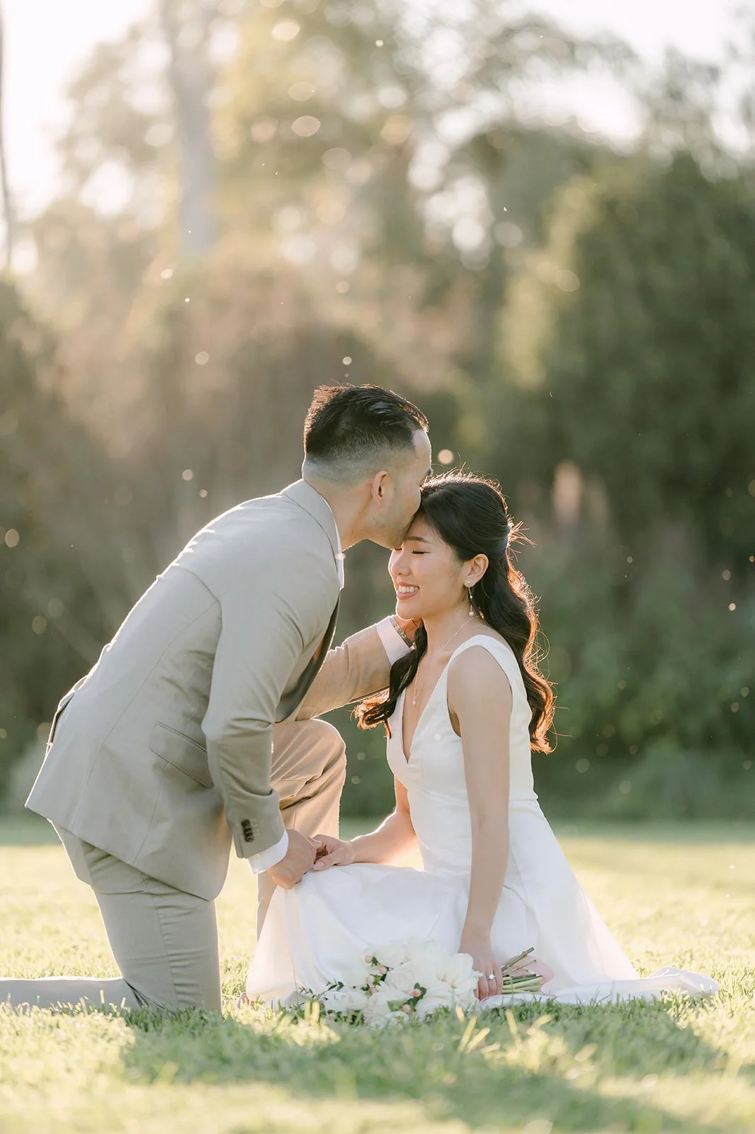 Vincent kneels beside Kim on the lawn in soft golden light.