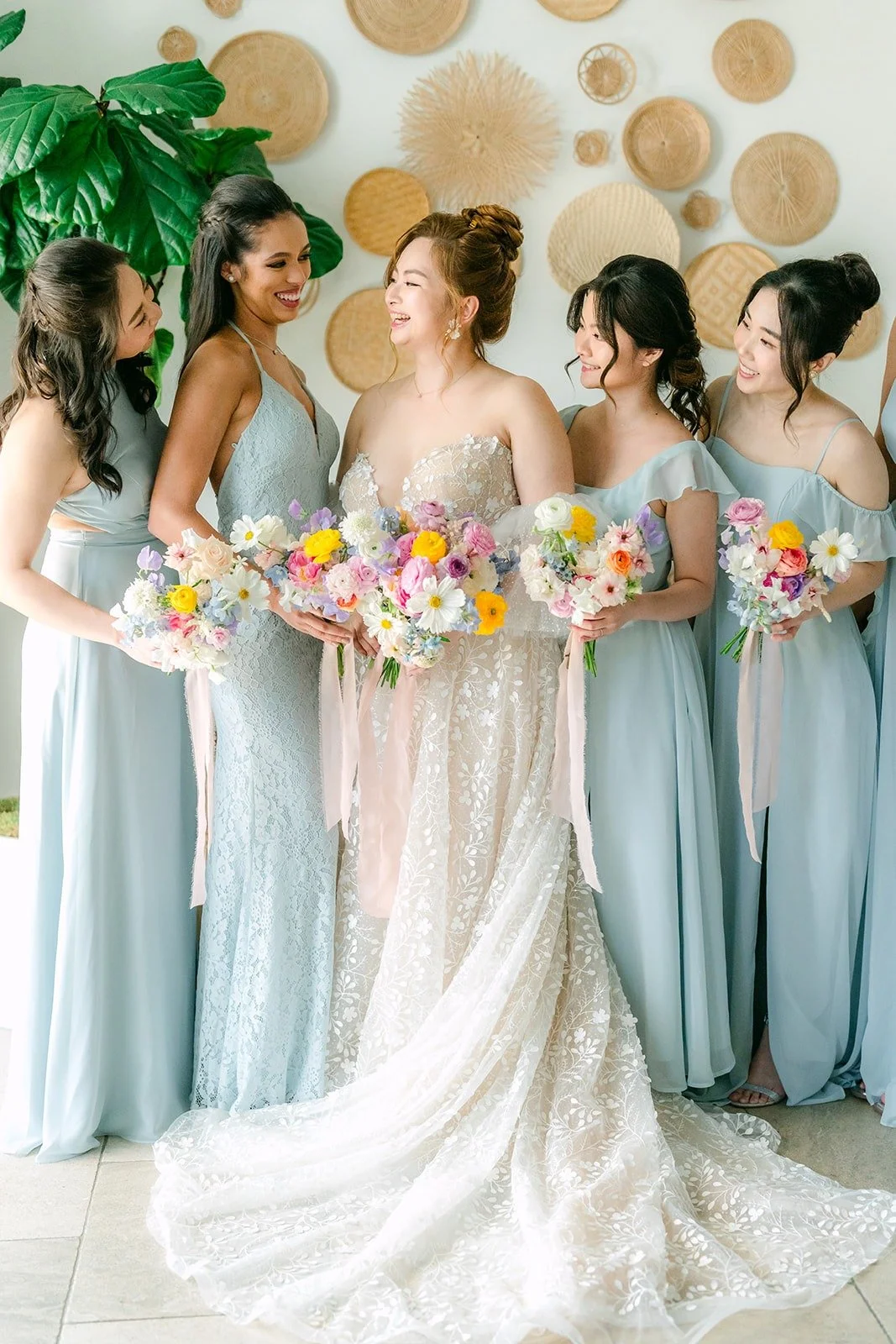 Joanna with her bridesmaids in dusty blue gowns, holding pastel bouquets