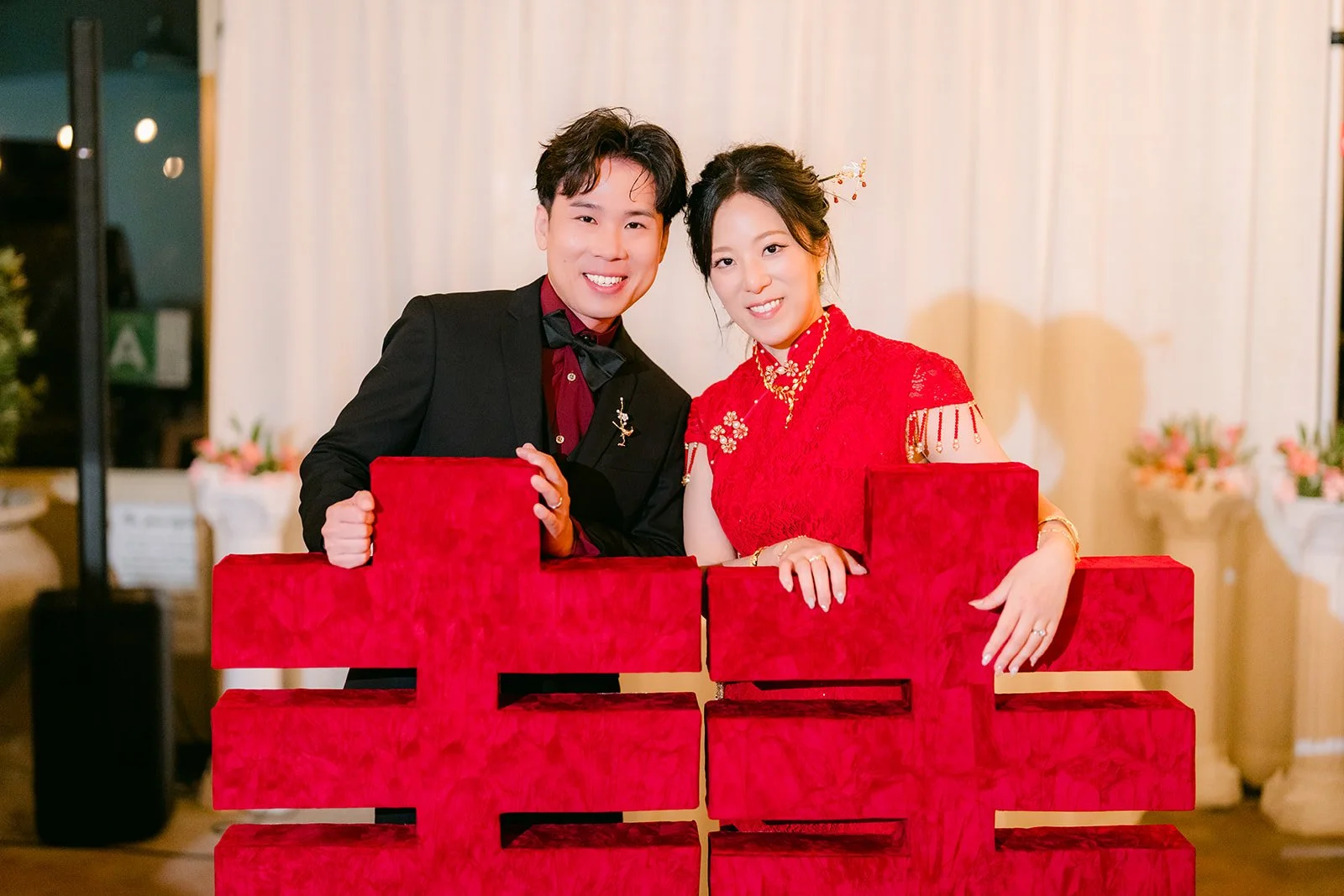 Elaine and Wen behind the red double happiness sign, photographed by One and Only Production.