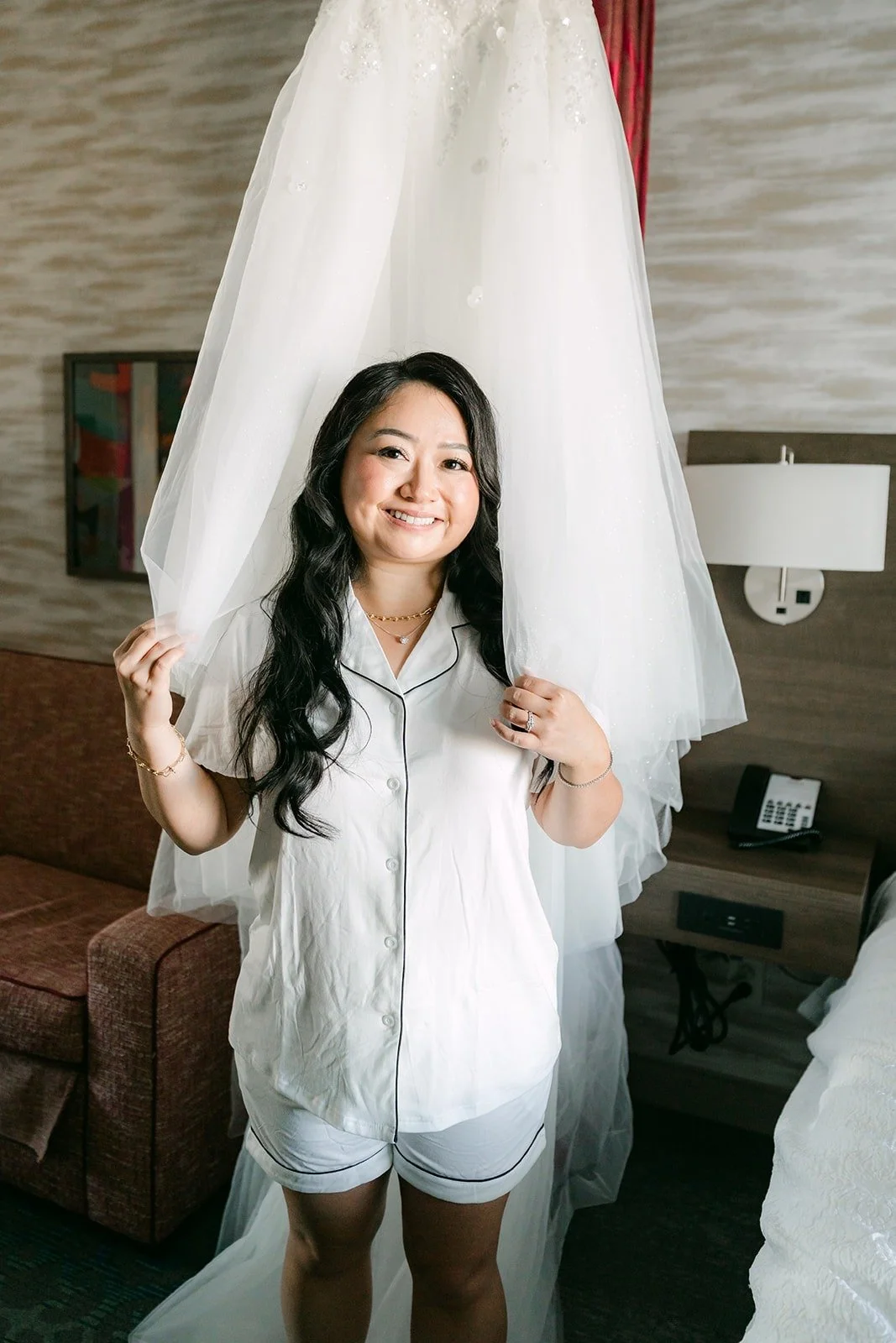 Jennifer in white pajamas peeks out from behind her gown