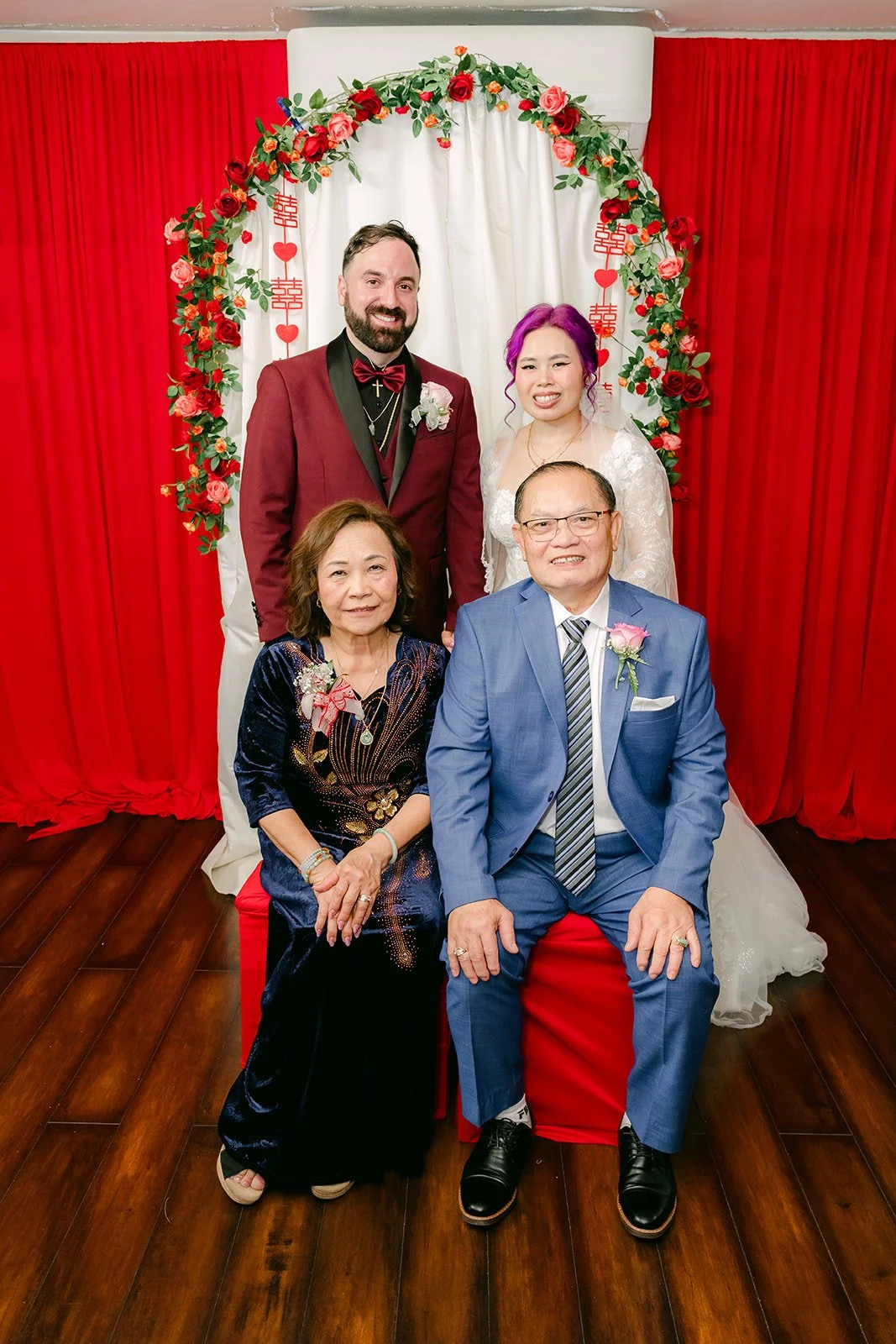 Vanessa and Ryan with Vanessa's parents under the rose arch.