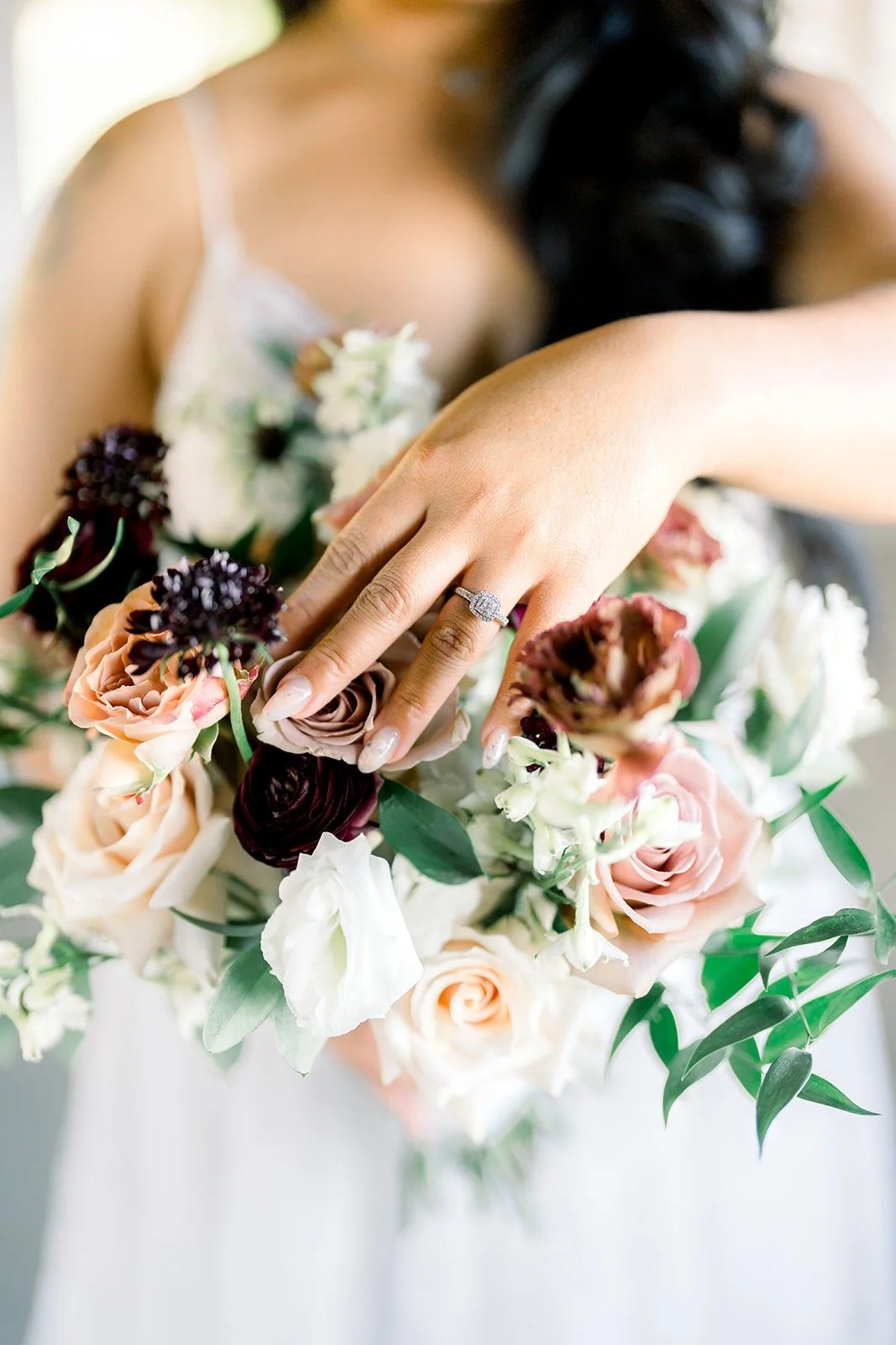 Close up of Betsy's hand on her bouquet of roses and ranunculus