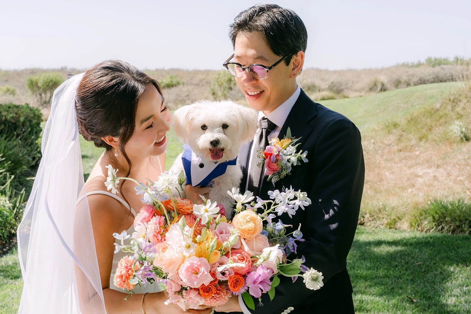 The newlyweds smiling down at their pup