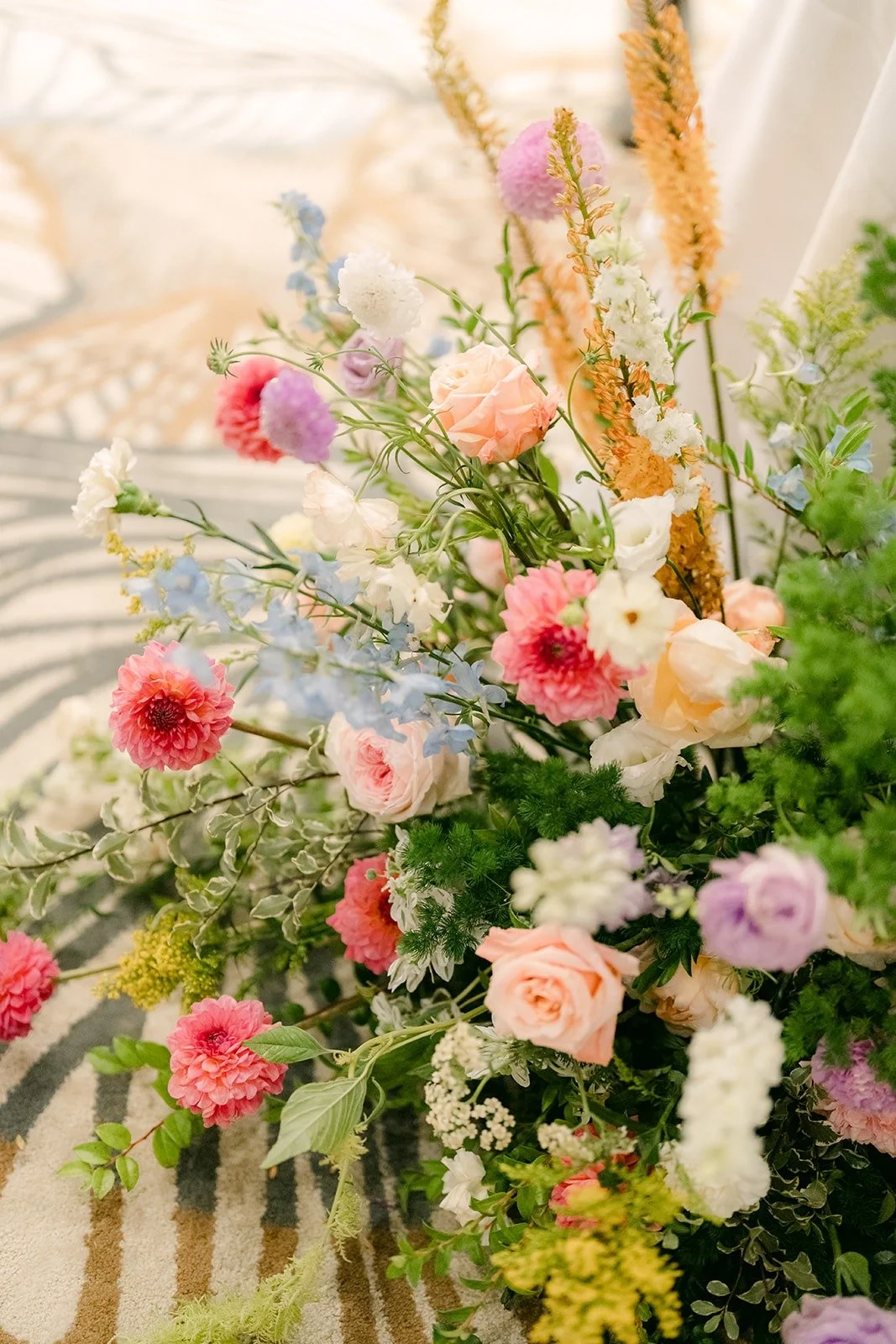 A tall arrangement of wildflowers, roses and dried grasses