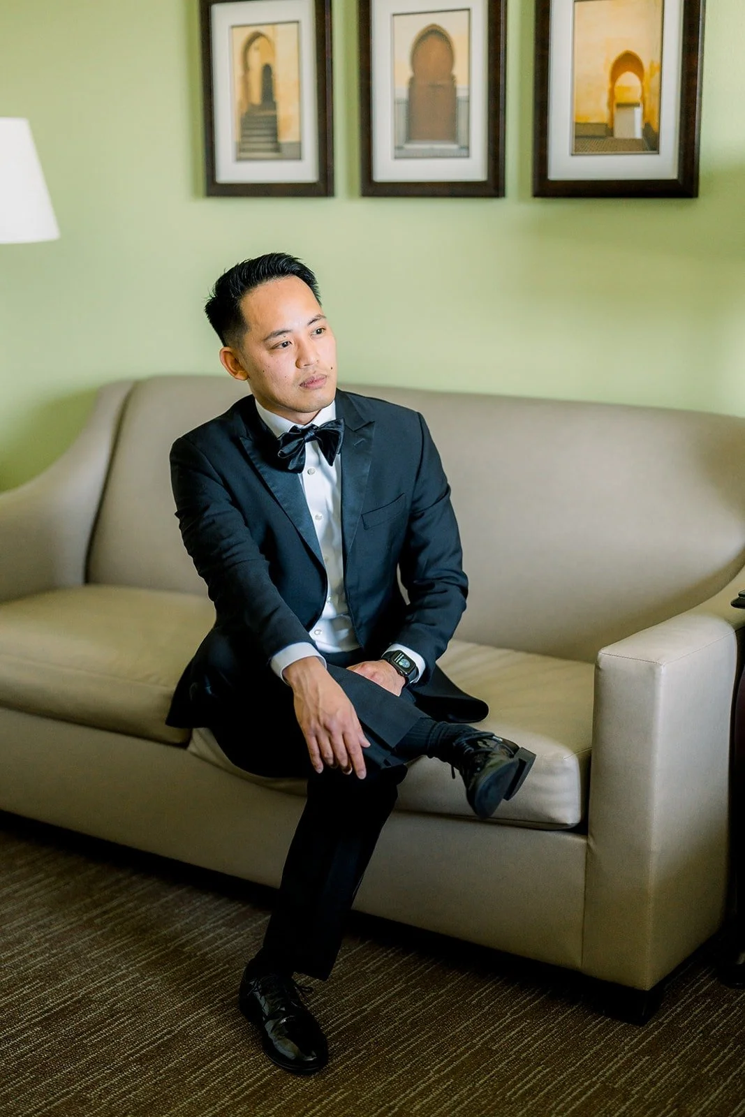 Ralph sitting on the sofa in his black tuxedo in the hotel suite