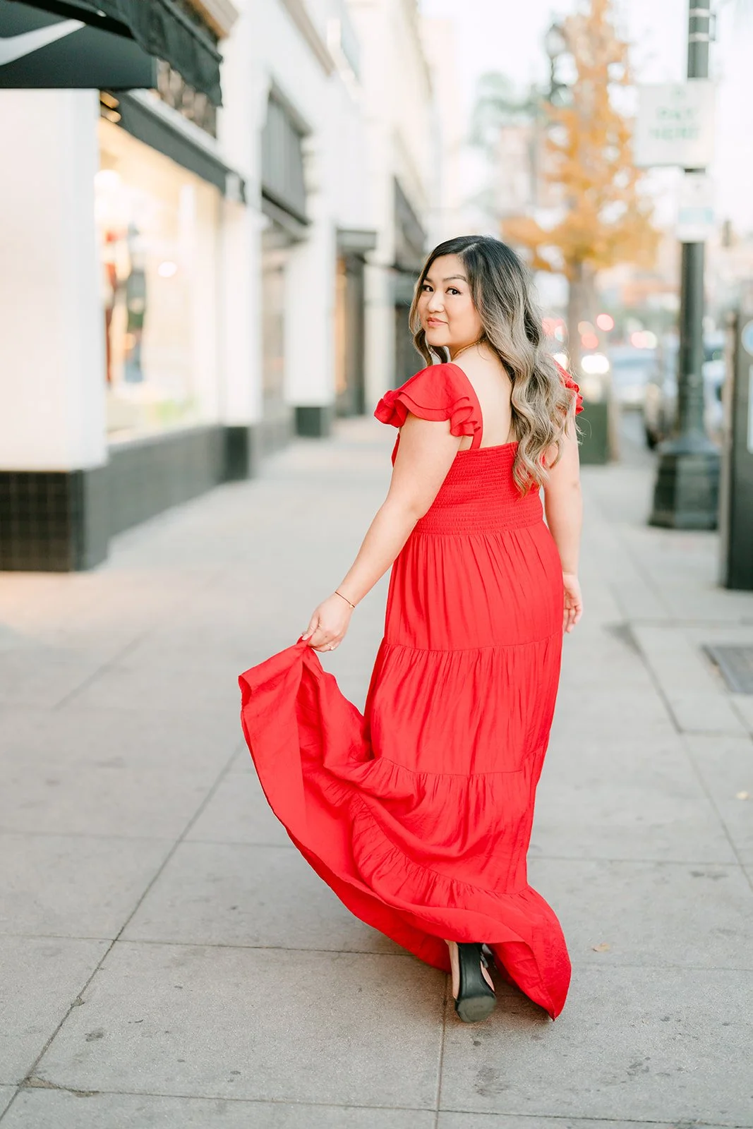 Linh swirls the skirt of her red dress on the sidewalk.