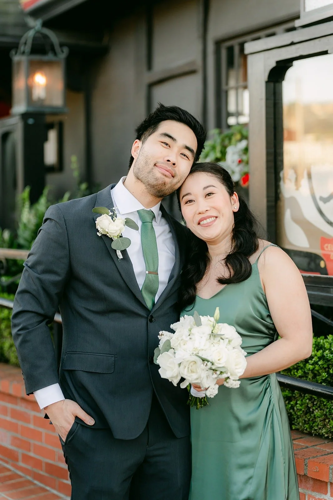 A bridesmaid and groomsman posing together outside the restaurant, photographed by One and Only Production