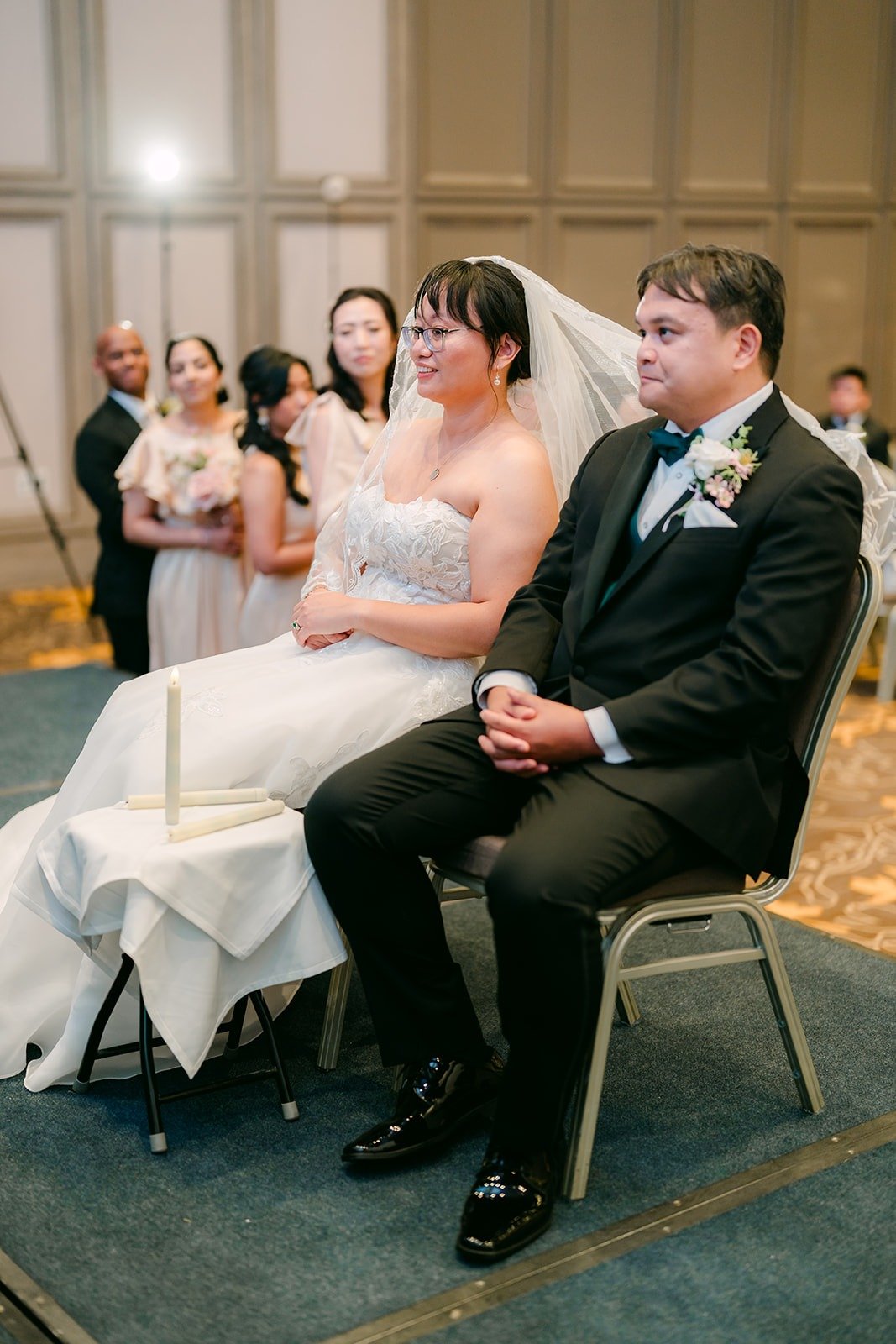 Stella and James seated together at the front of the ballroom, smiling at a reading
