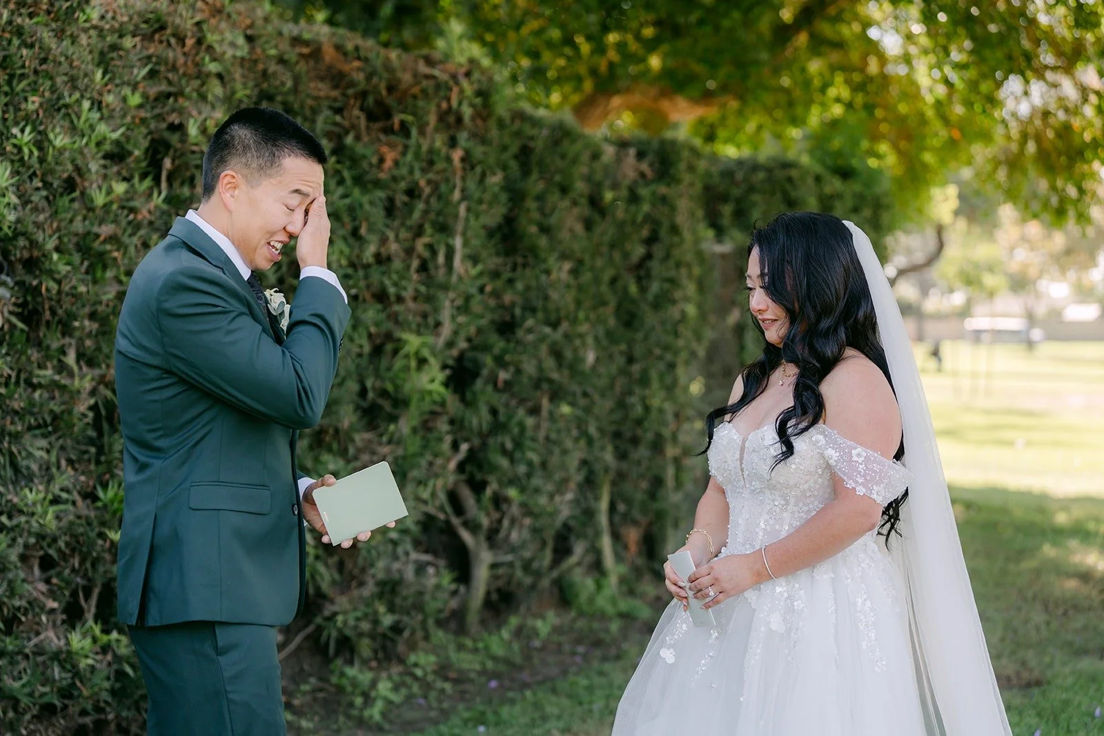 Kevin wipes a tear while Jennifer reads her vows by the hedge