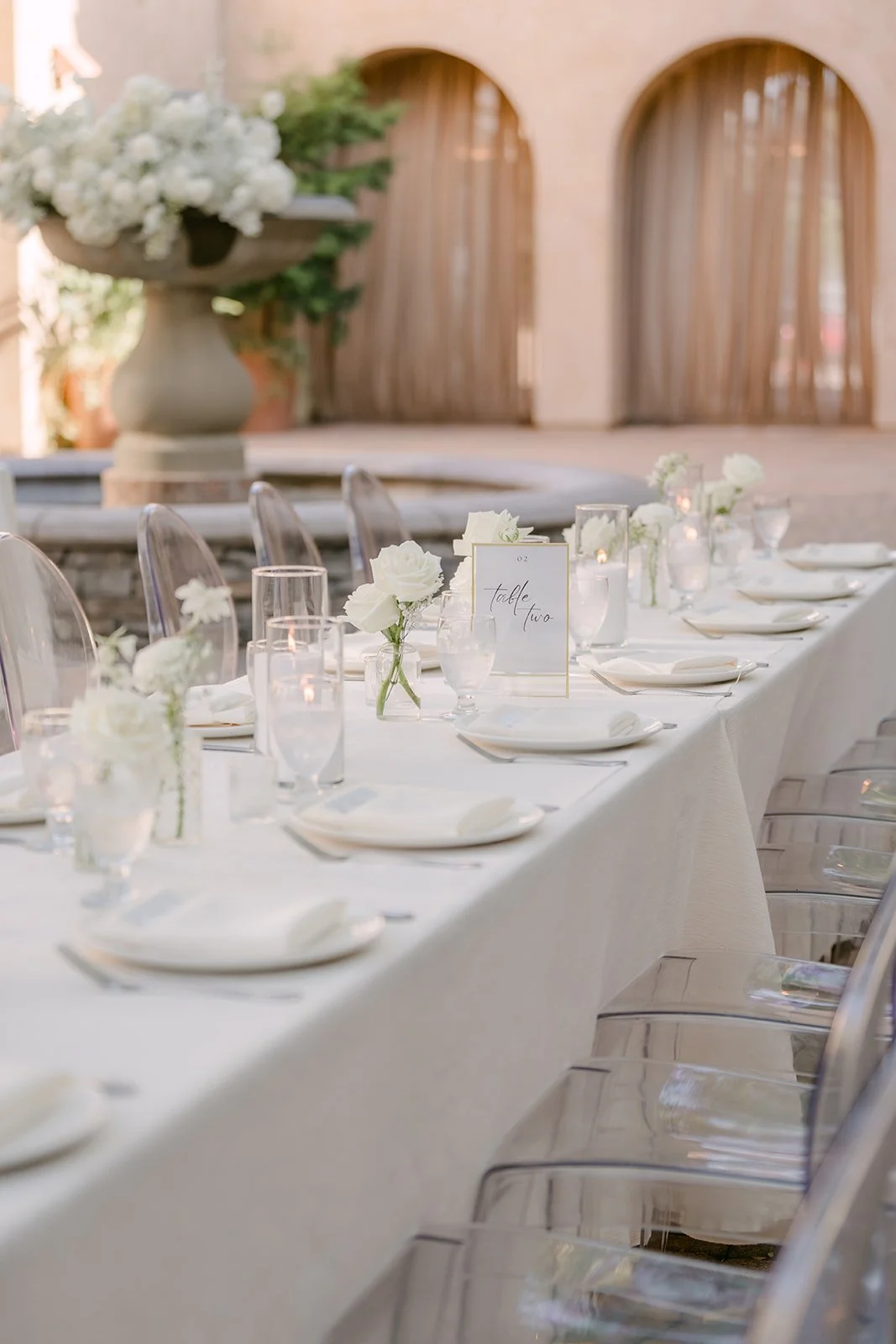 Long reception table with white florals in front of the arches