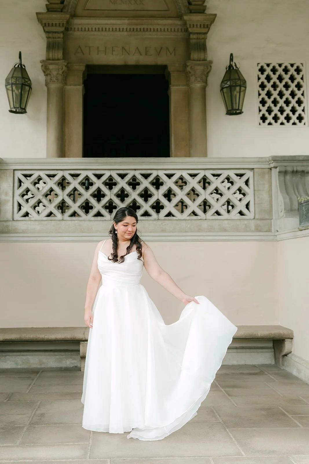 Saira lifting her skirt in front of a carved lattice wall